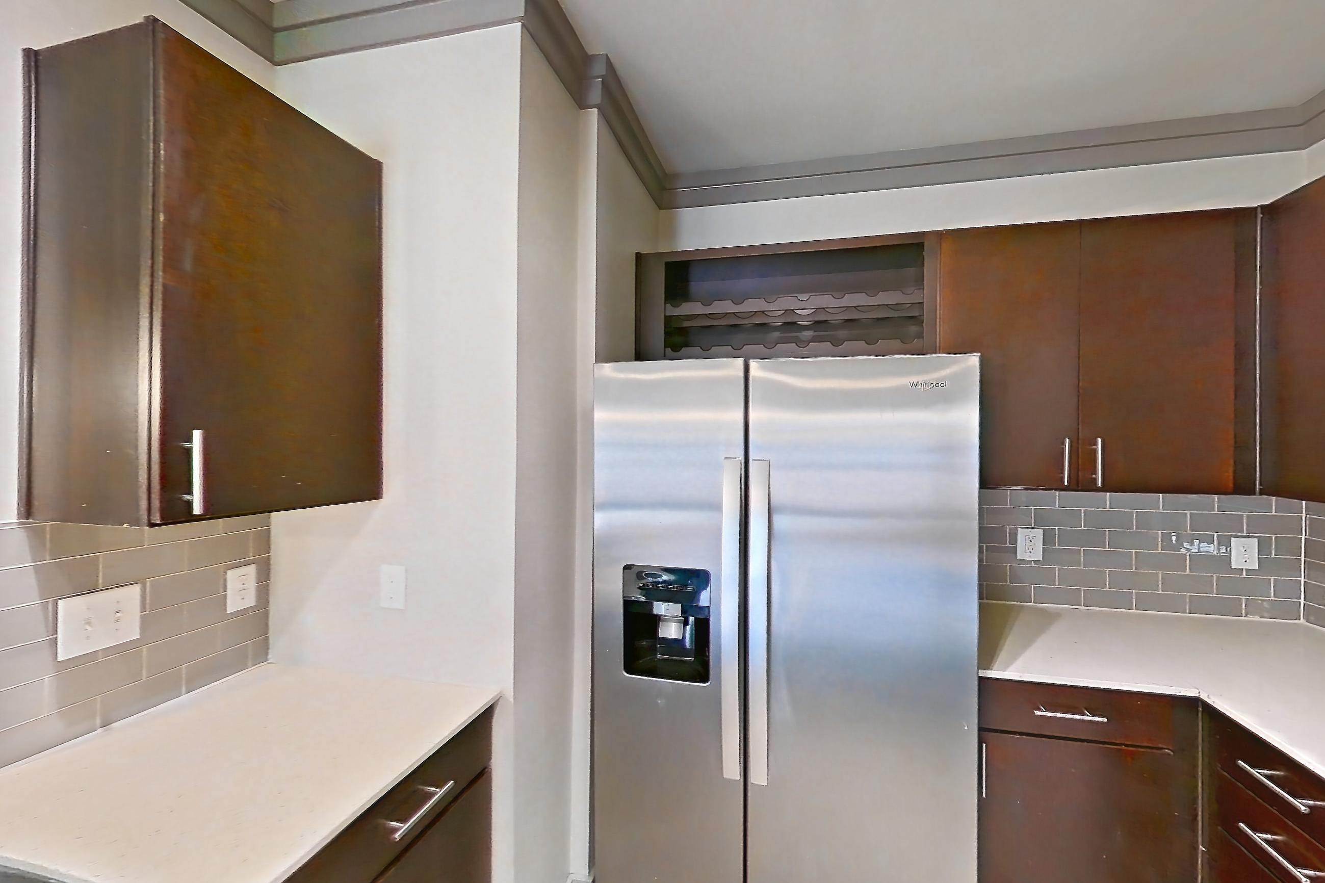 Kitchen with dishwasher, light stone countertops, light wood-finish flooring, refrigerator, stainless steel appliances, and water & ice dispenser, Apartment 3104 at Cortland Phillips Creek Ranch