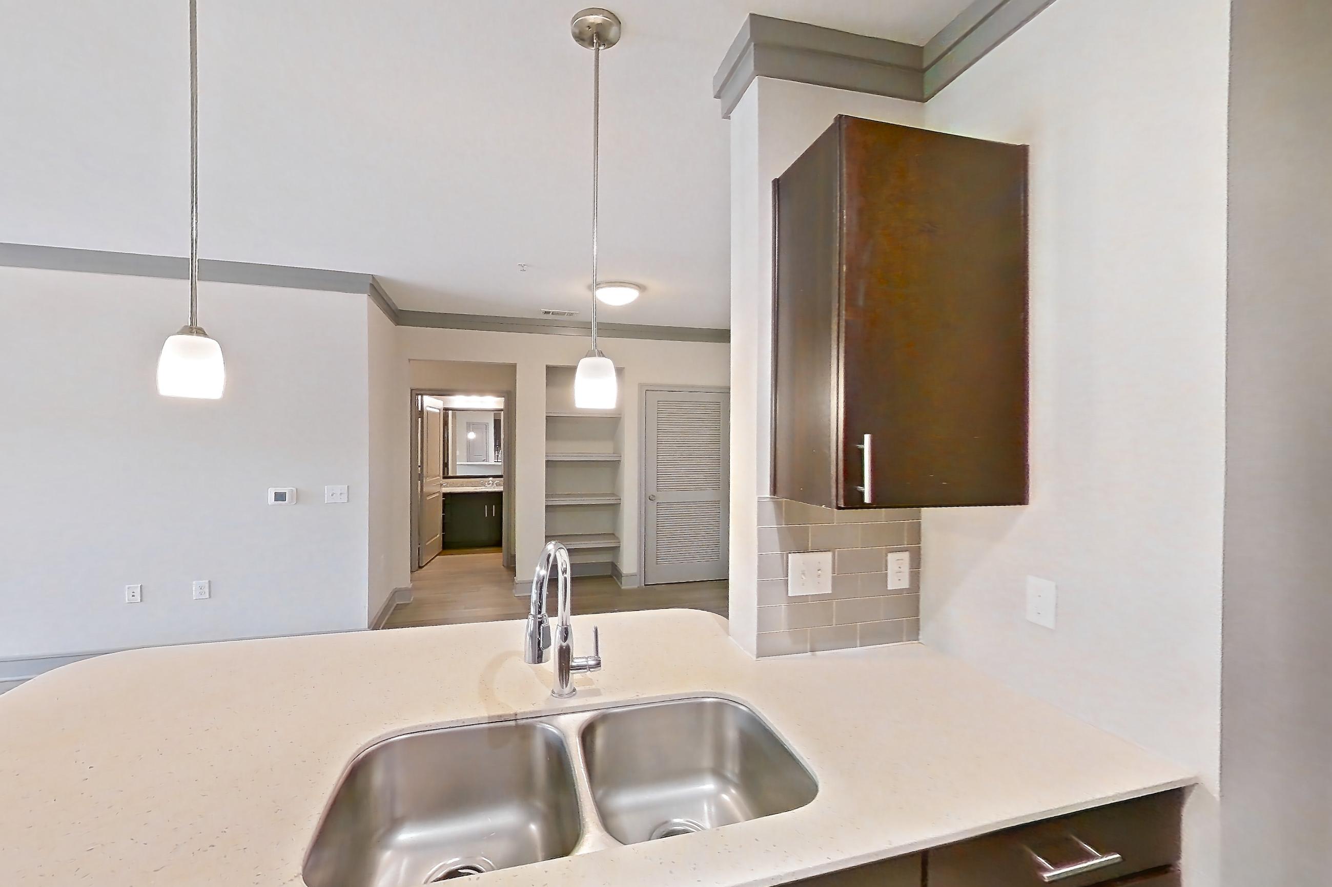 Kitchen with dishwasher, light stone countertops, light wood-finish flooring, refrigerator, stainless steel appliances, and water & ice dispenser, Apartment 3104 at Cortland Phillips Creek Ranch