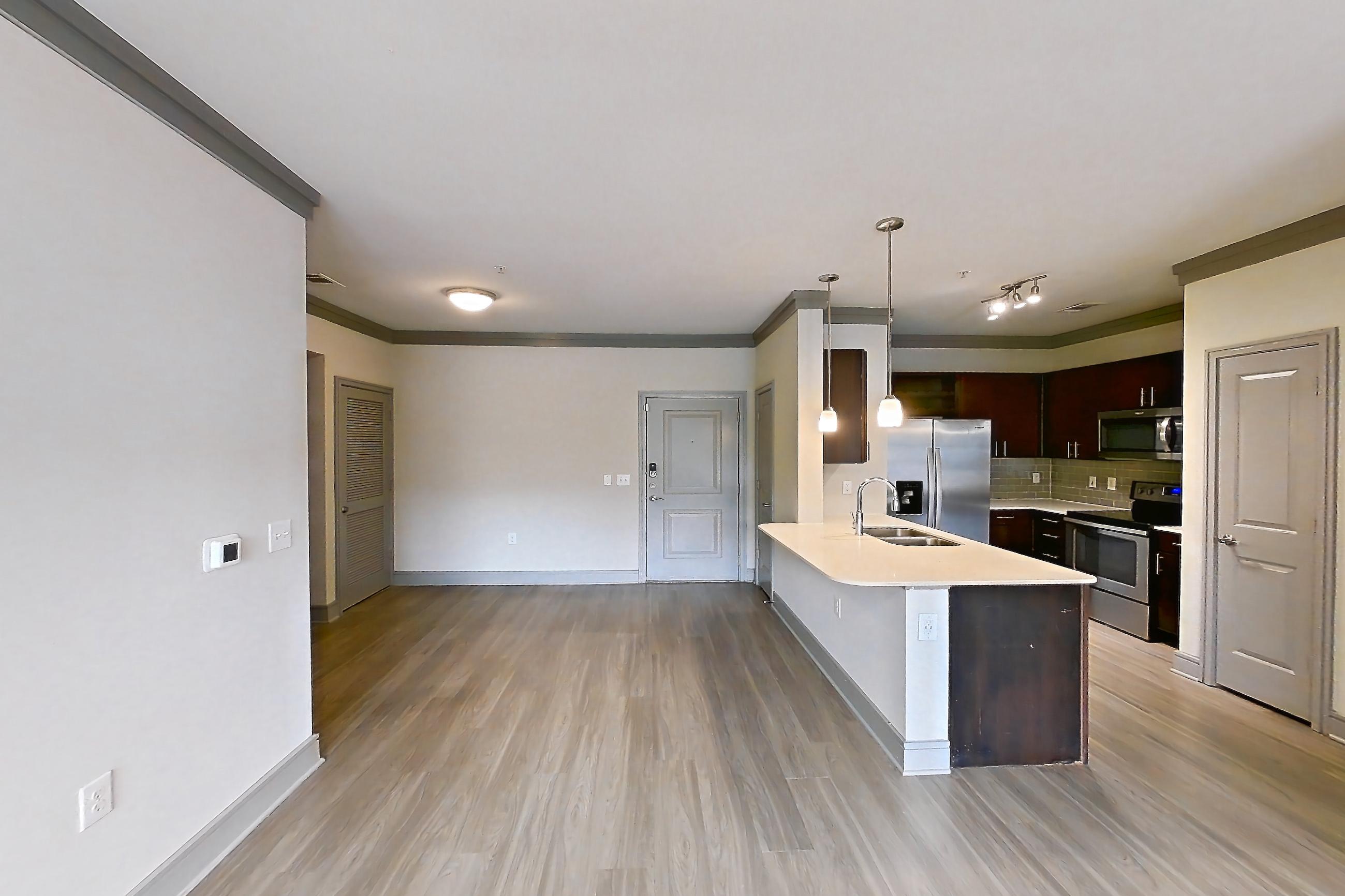 Living room with electric range, light stone countertops, light wood-finish flooring, oven/range, refrigerator, stainless steel appliances, and water & ice dispenser, Apartment 3104 at Cortland Phillips Creek Ranch