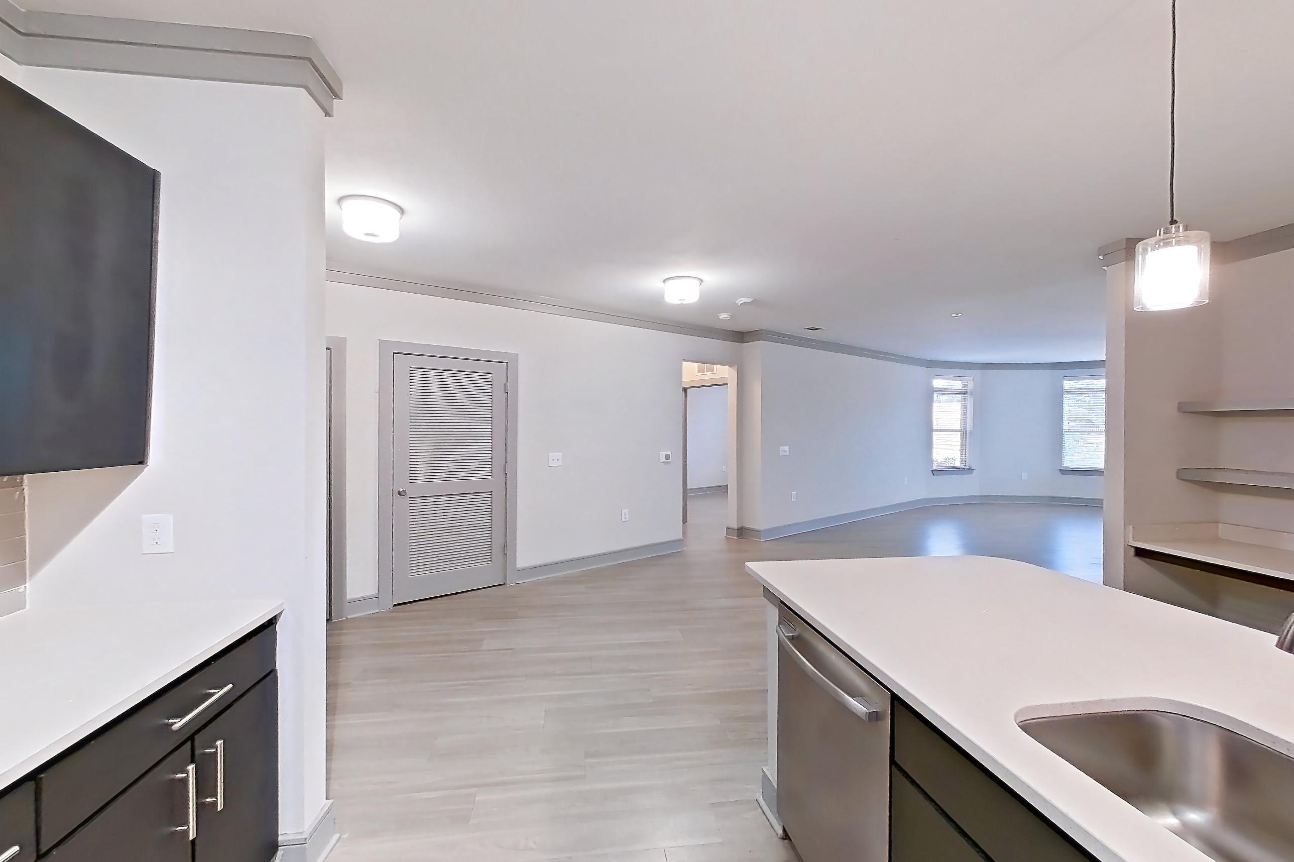 Kitchen with dishwasher, electric range, light countertops, light stone countertops, light wood-finish flooring, microwave, oven/range, and stainless steel appliances, Apartment 12207 at Cortland Phillips Creek Ranch