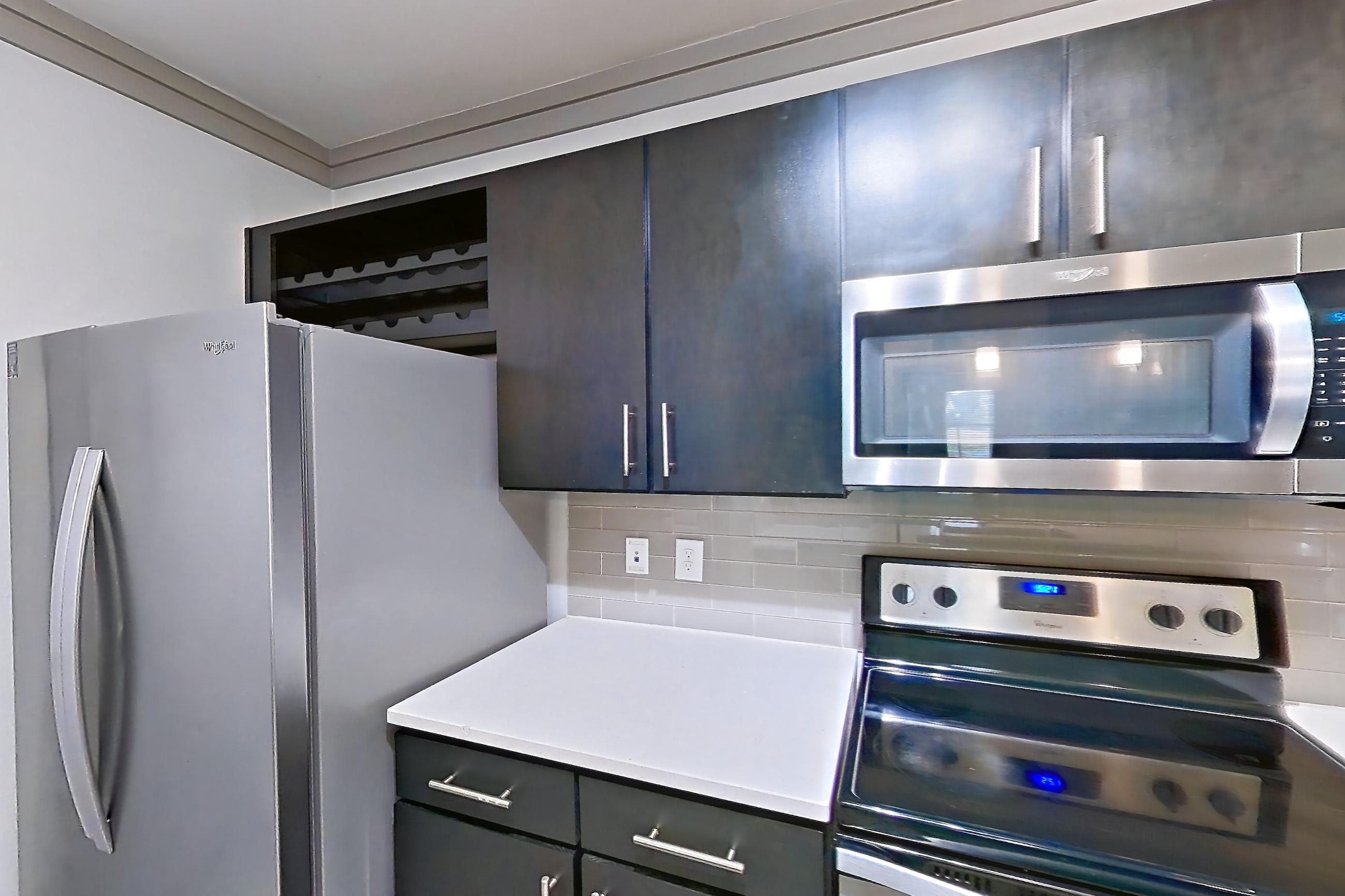 Kitchen with dishwasher, electric range, light countertops, light stone countertops, light wood-finish flooring, microwave, oven/range, and stainless steel appliances, Apartment 12207 at Cortland Phillips Creek Ranch