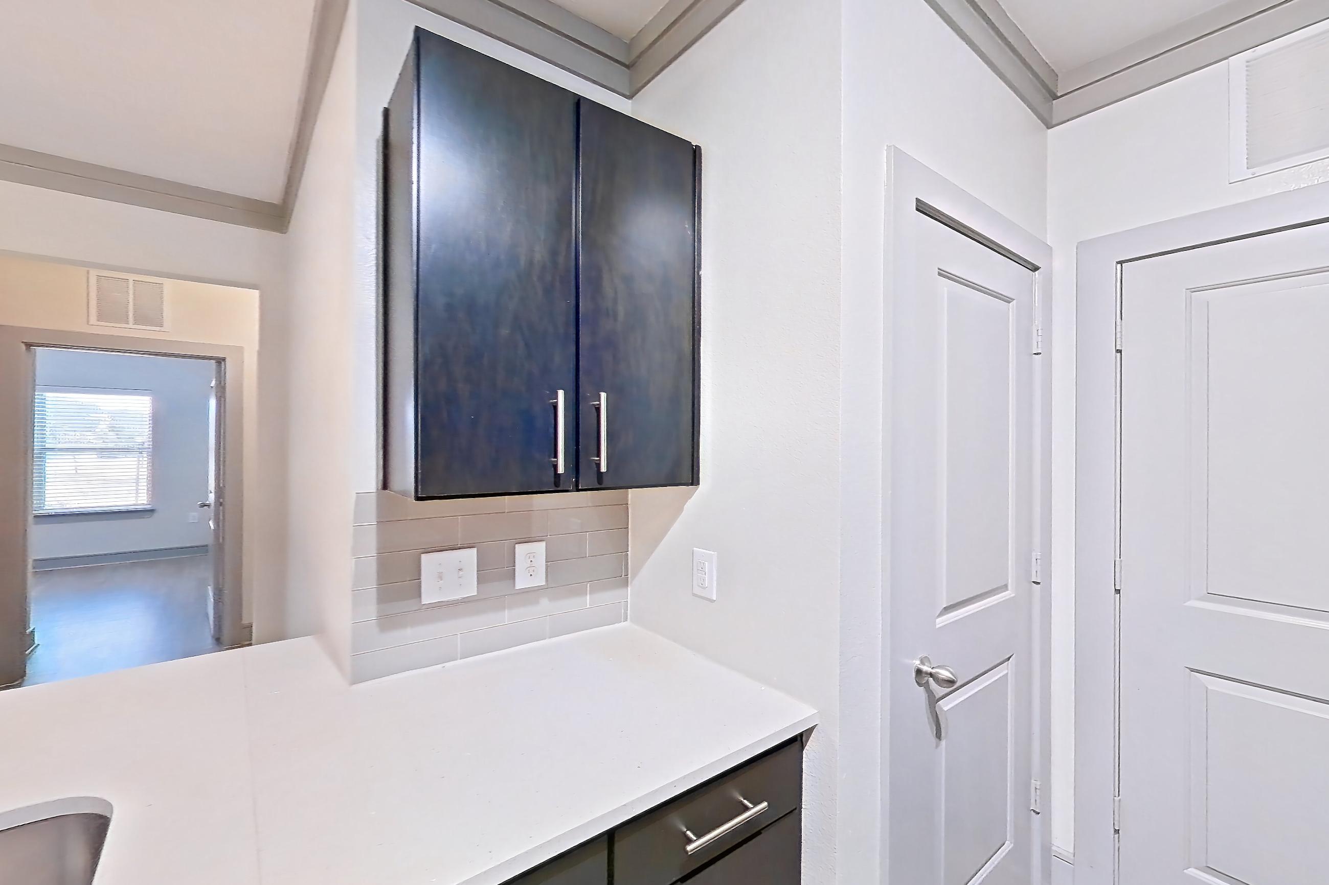 Kitchen with dishwasher, electric range, light countertops, light stone countertops, light wood-finish flooring, microwave, oven/range, and stainless steel appliances, Apartment 12207 at Cortland Phillips Creek Ranch