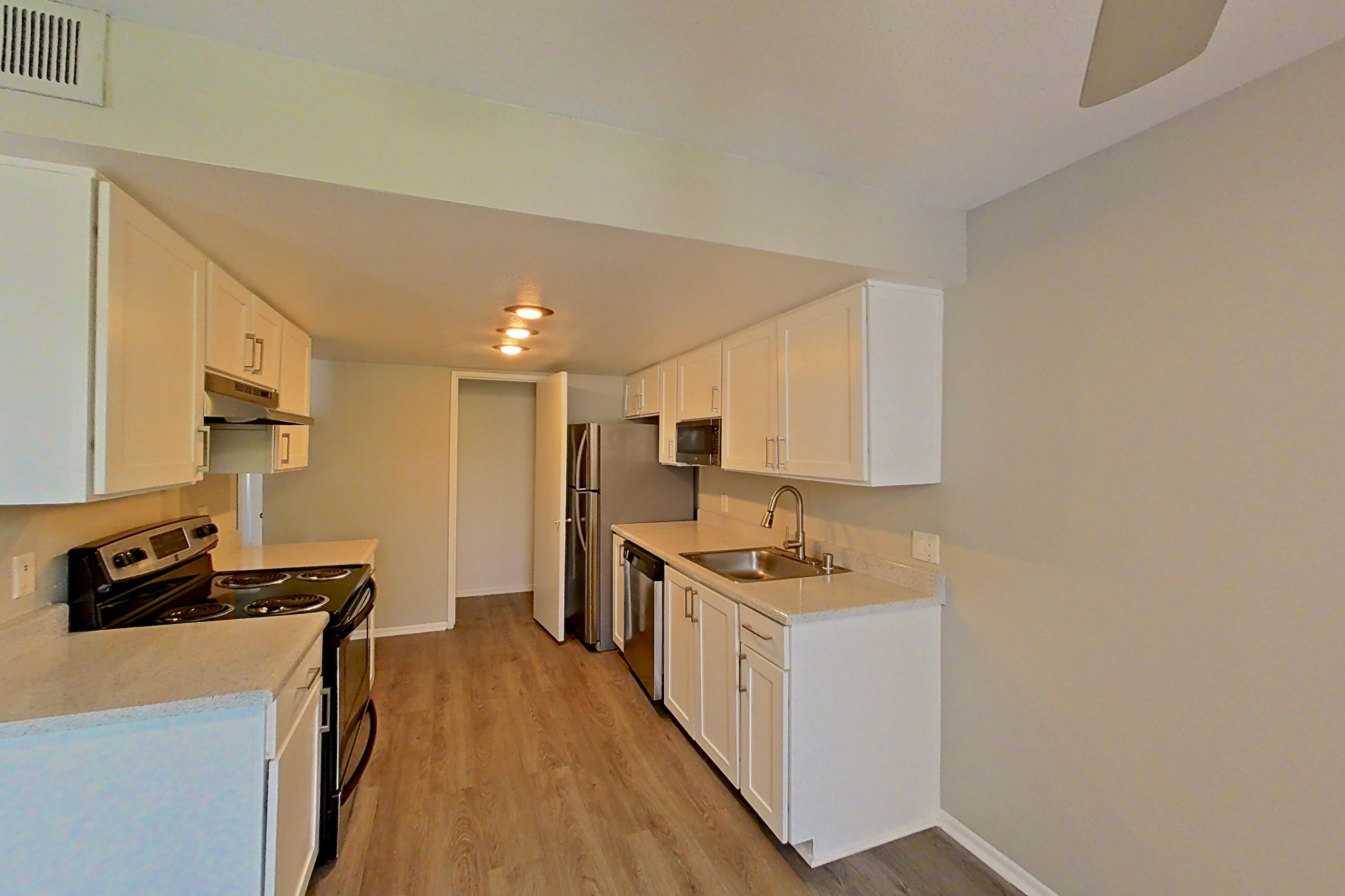 Dining area with dark wood-finish flooring, dishwasher, electric range, light countertops, light wood-finish flooring, and stainless steel appliances, Apartment 03 at Avana Rancho Cucamonga