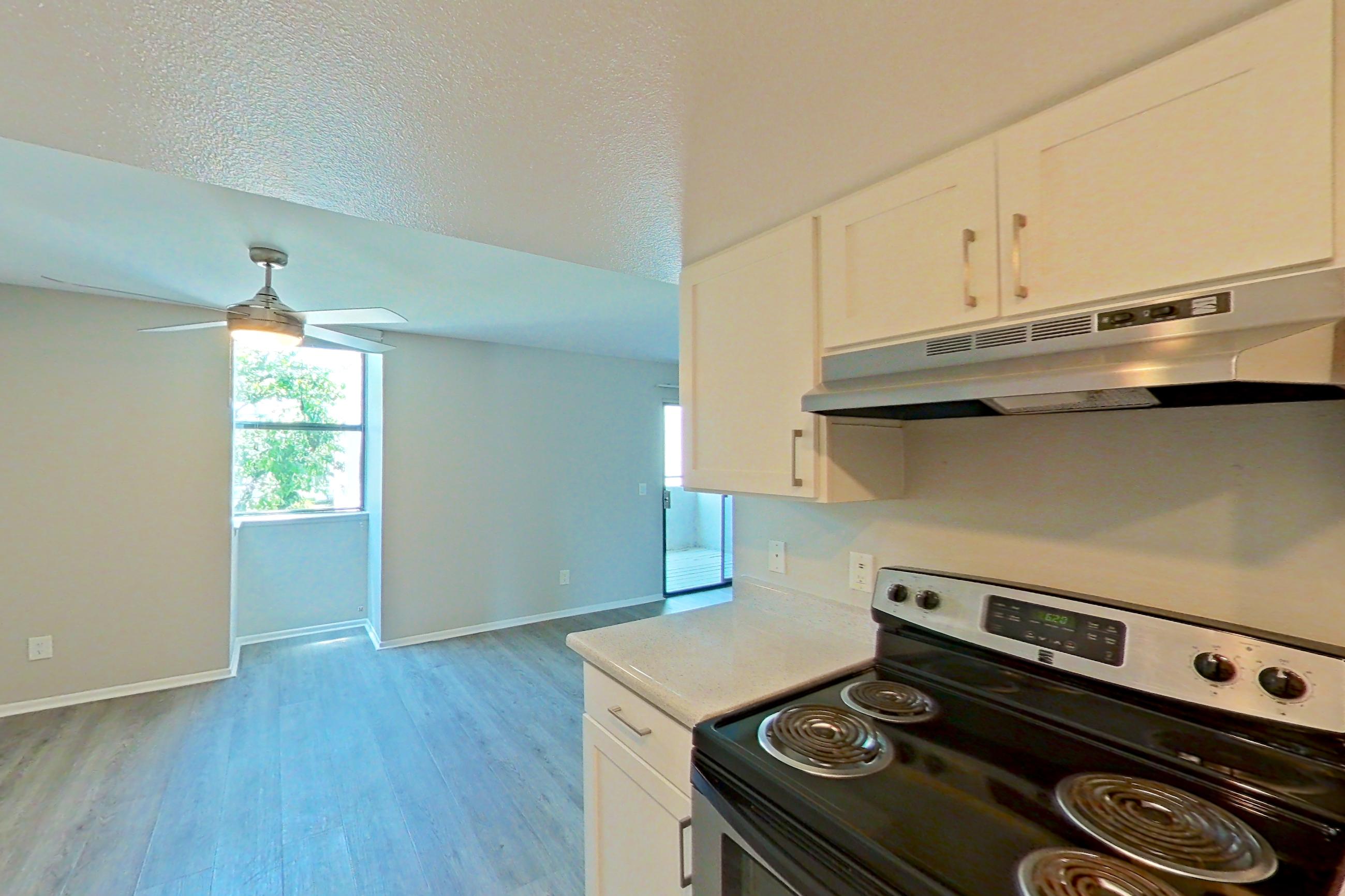 Kitchen with dishwasher, electric range, light countertops, light stone countertops, light wood-finish flooring, microwave, oven/range, range hood, refrigerator, and stainless steel appliances, Apartment 03 at Avana Rancho Cucamonga