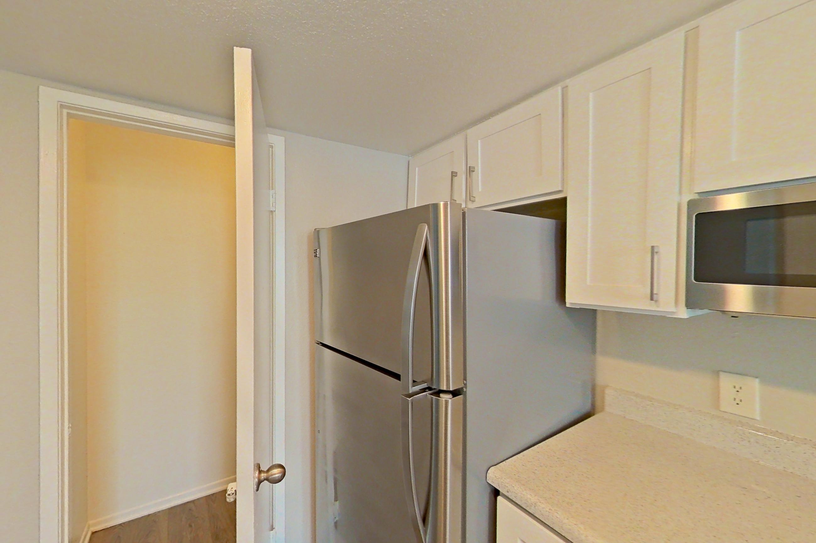 Kitchen with dishwasher, electric range, light countertops, light stone countertops, light wood-finish flooring, microwave, oven/range, range hood, refrigerator, and stainless steel appliances, Apartment 03 at Avana Rancho Cucamonga