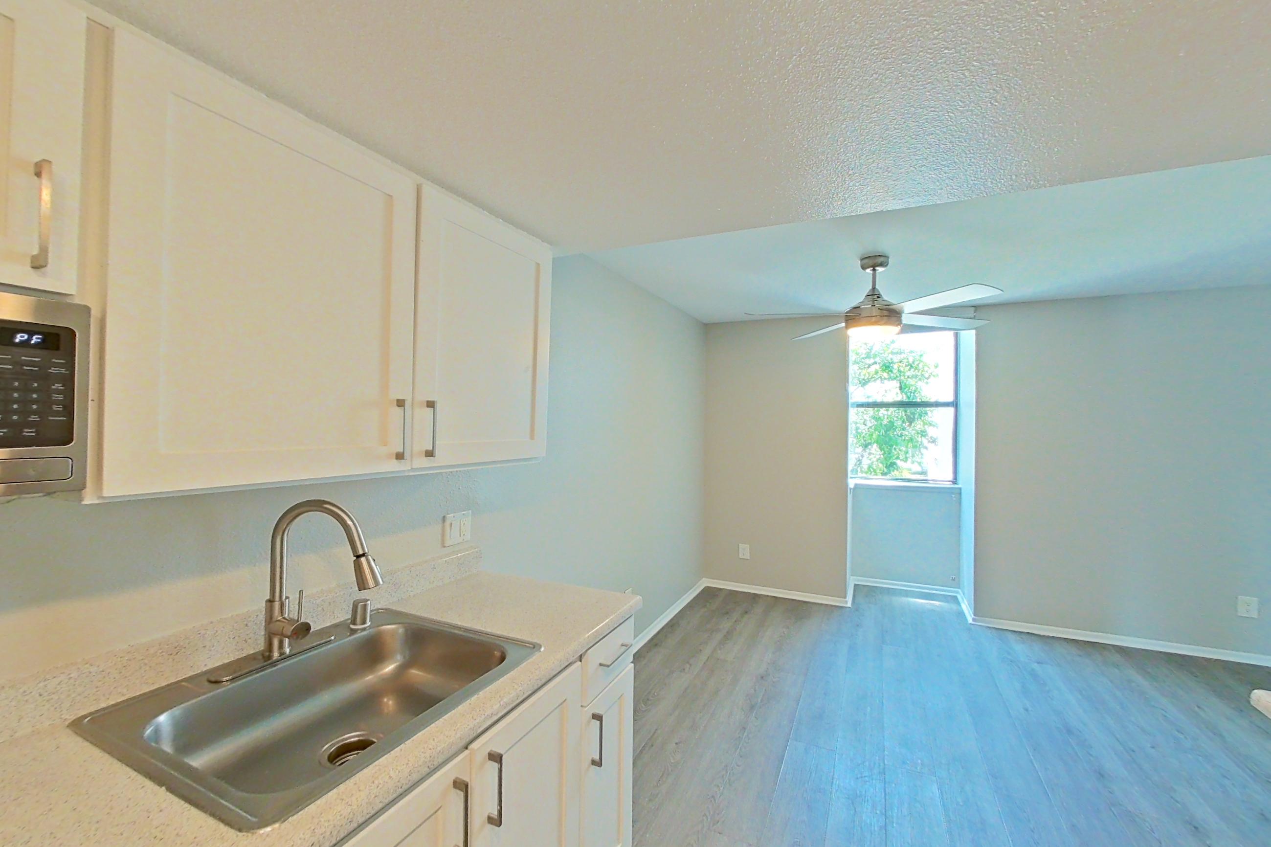 Kitchen with dishwasher, electric range, light countertops, light stone countertops, light wood-finish flooring, microwave, oven/range, range hood, refrigerator, and stainless steel appliances, Apartment 03 at Avana Rancho Cucamonga