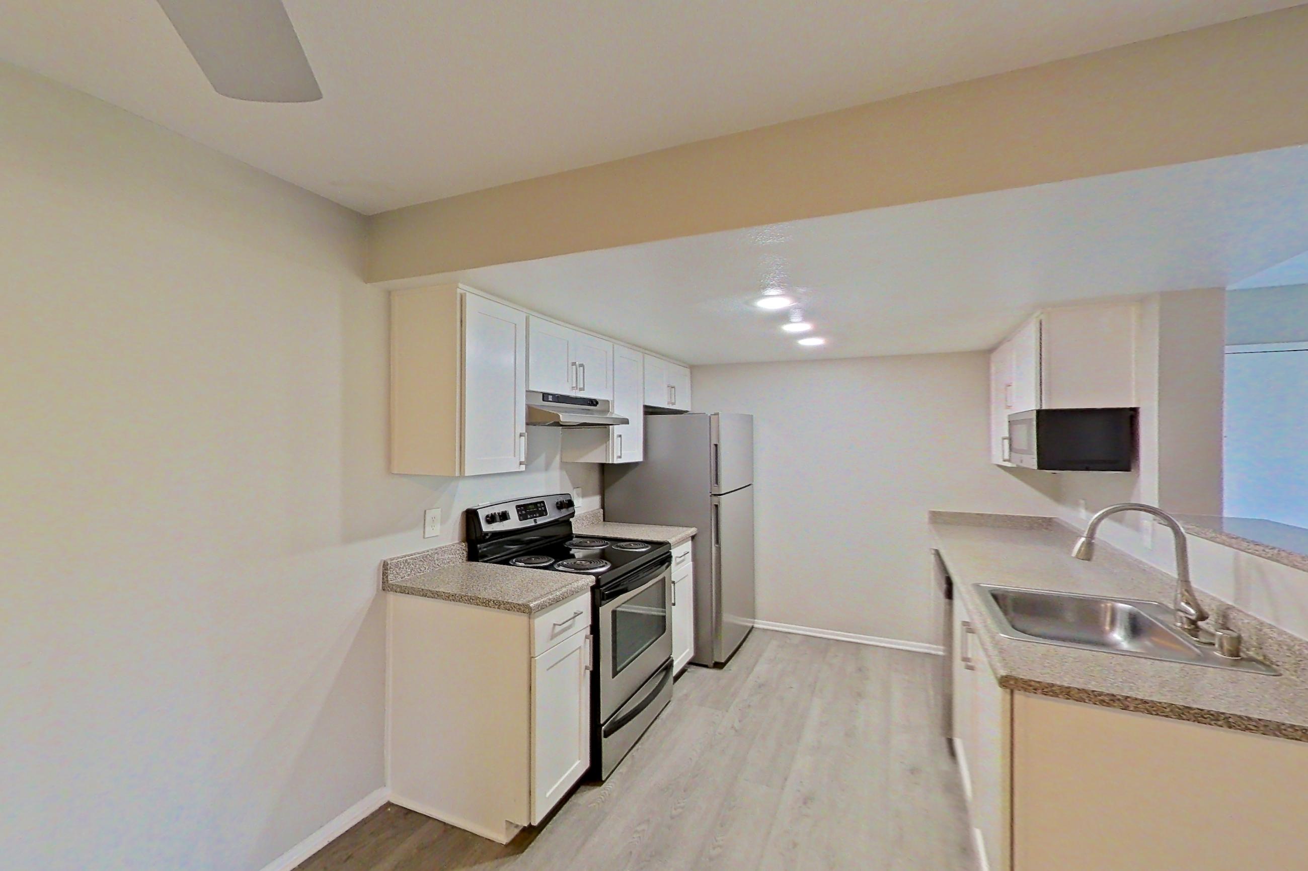 Dining area with electric range, light countertops, light wood-finish flooring, oven/range, refrigerator, stainless steel appliances, and white appliances, Apartment 12 at Avana Rancho Cucamonga