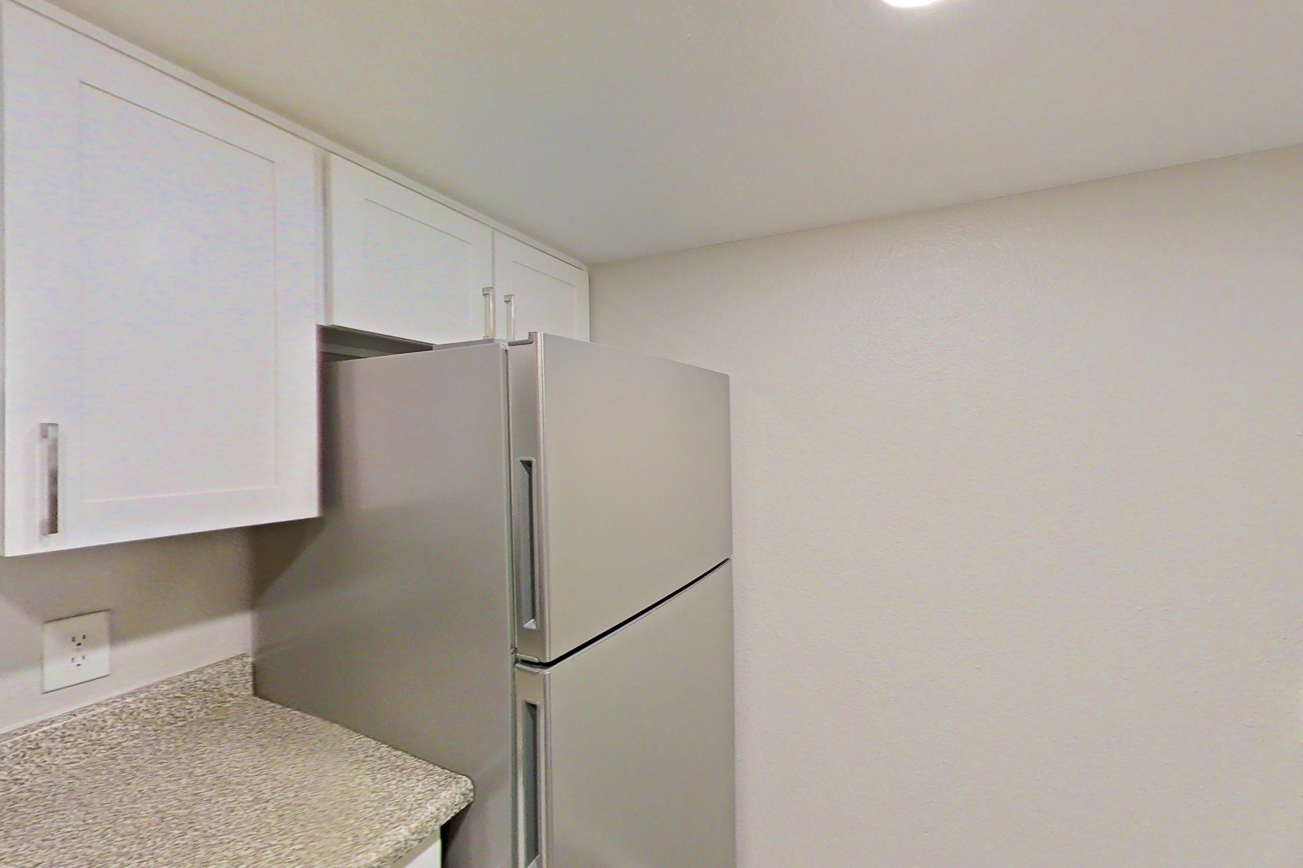 Kitchen with dishwasher, electric range, light countertops, light stone countertops, light wood-finish flooring, oven/range, refrigerator, and stainless steel appliances, Apartment 12 at Avana Rancho Cucamonga
