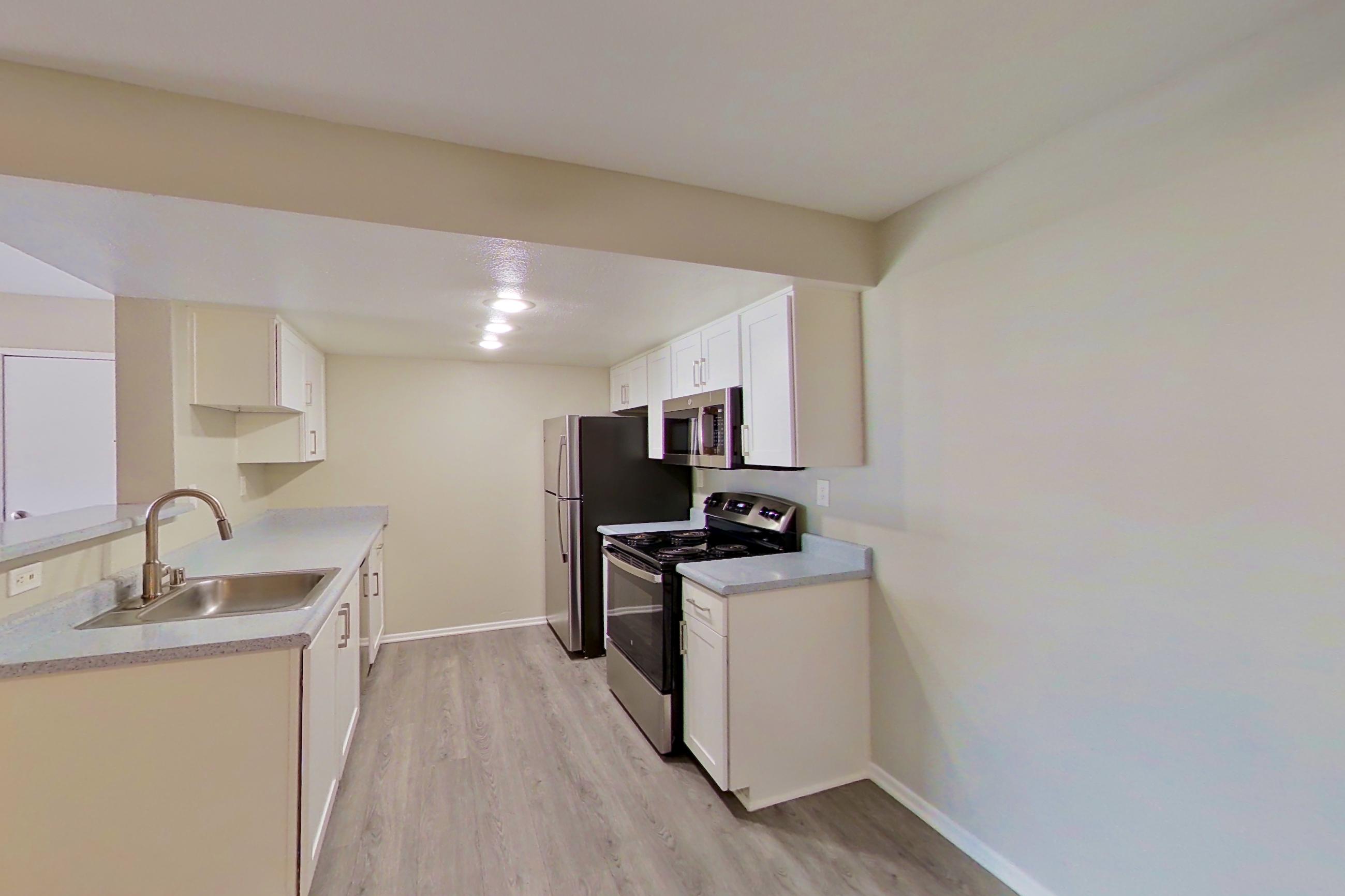 Dining area with electric range, light countertops, light wood-finish flooring, oven/range, refrigerator, and stainless steel appliances, Apartment 06 at Avana Rancho Cucamonga