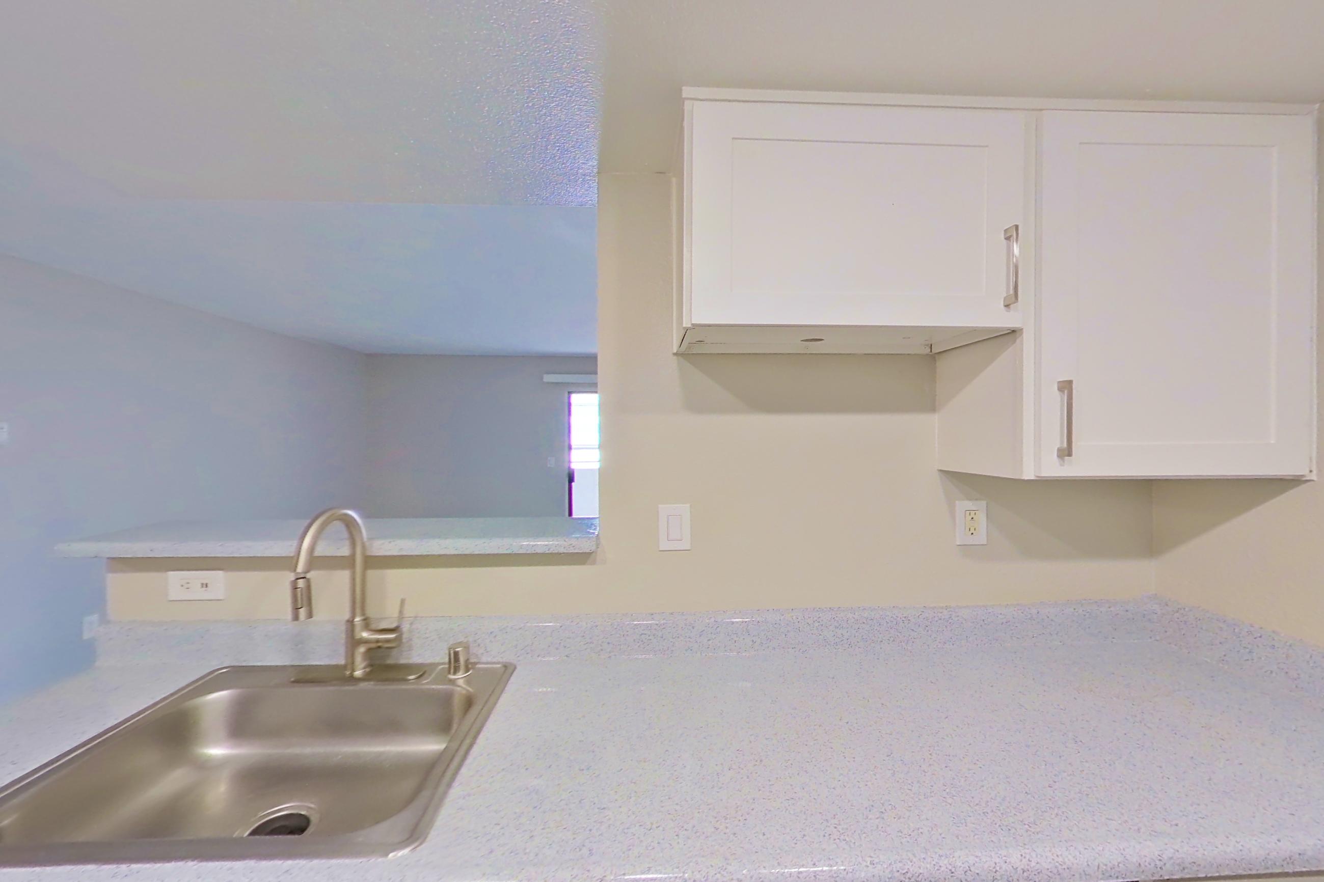 Kitchen with dishwasher, electric range, light countertops, light wood-finish flooring, microwave, oven/range, refrigerator, and stainless steel appliances, Apartment 06 at Avana Rancho Cucamonga