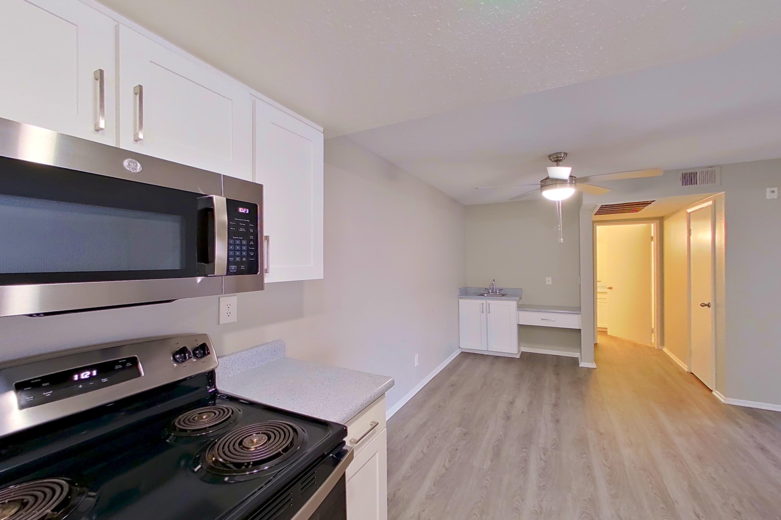 Kitchen with dishwasher, electric range, light countertops, light wood-finish flooring, microwave, oven/range, refrigerator, and stainless steel appliances, Apartment 06 at Avana Rancho Cucamonga