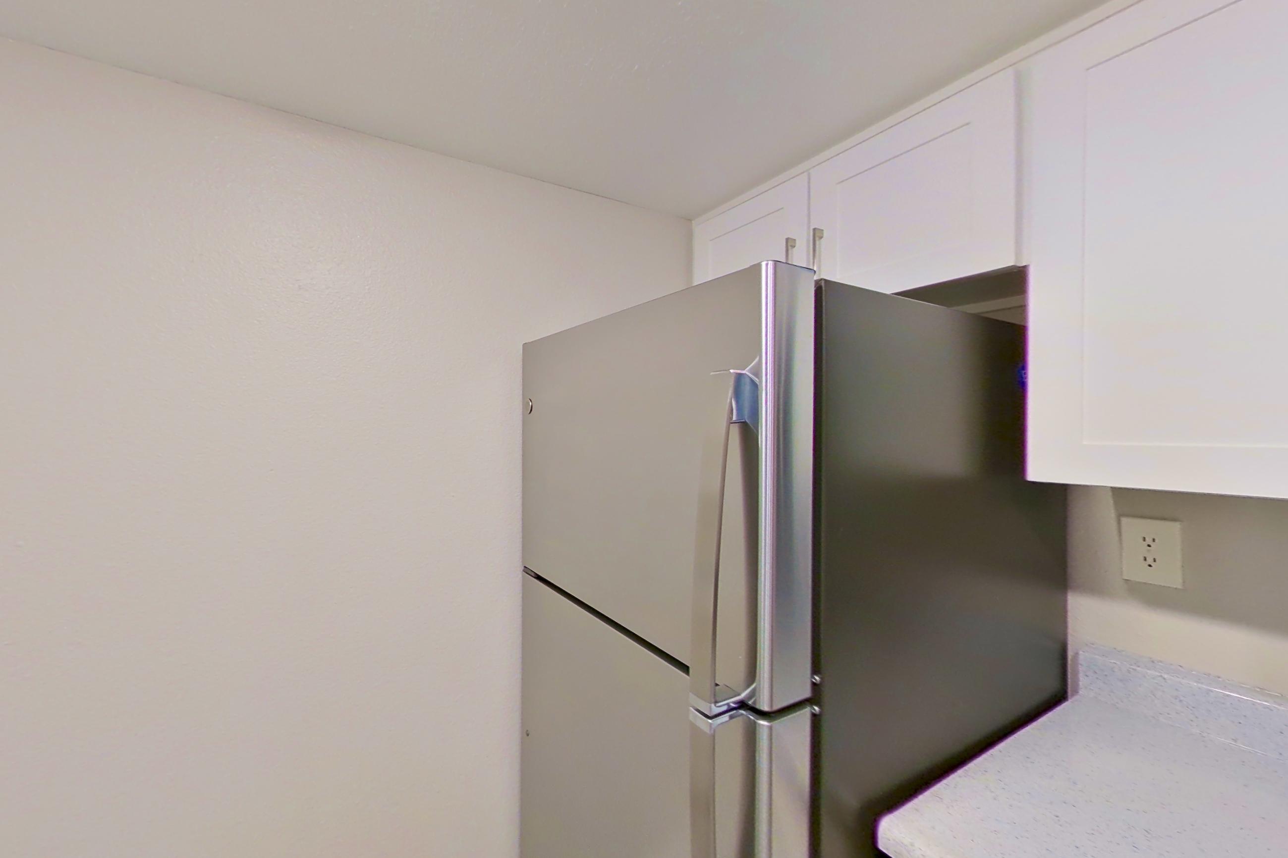 Kitchen with dishwasher, electric range, light countertops, light wood-finish flooring, microwave, oven/range, refrigerator, and stainless steel appliances, Apartment 06 at Avana Rancho Cucamonga