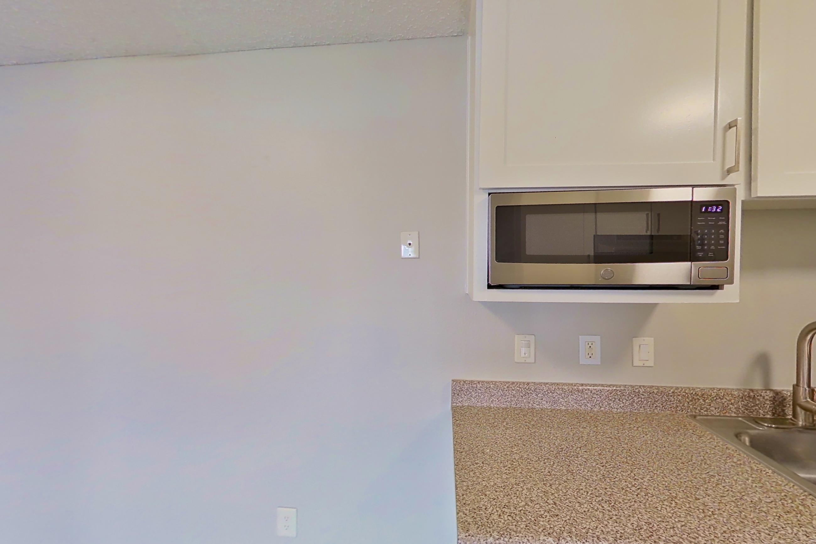 Kitchen with dishwasher, electric range, fireplace, light stone countertops, light wood-finish flooring, oven/range, and stainless steel appliances, Apartment 08-06 at Avana Rancho Cucamonga
