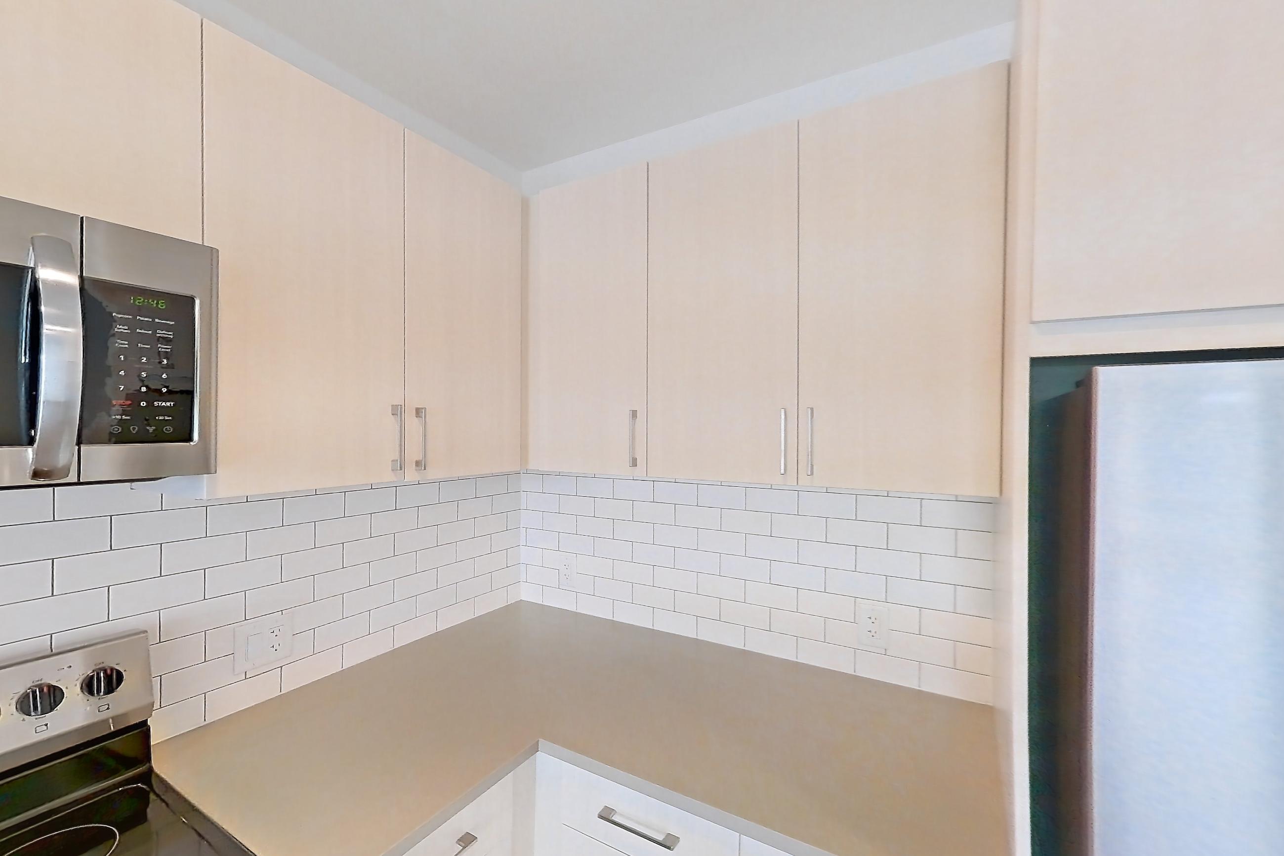 Kitchen with dishwasher, electric range, light countertops, light wood-finish flooring, microwave, oven/range, refrigerator, and stainless steel appliances, Apartment 440 at Braxton