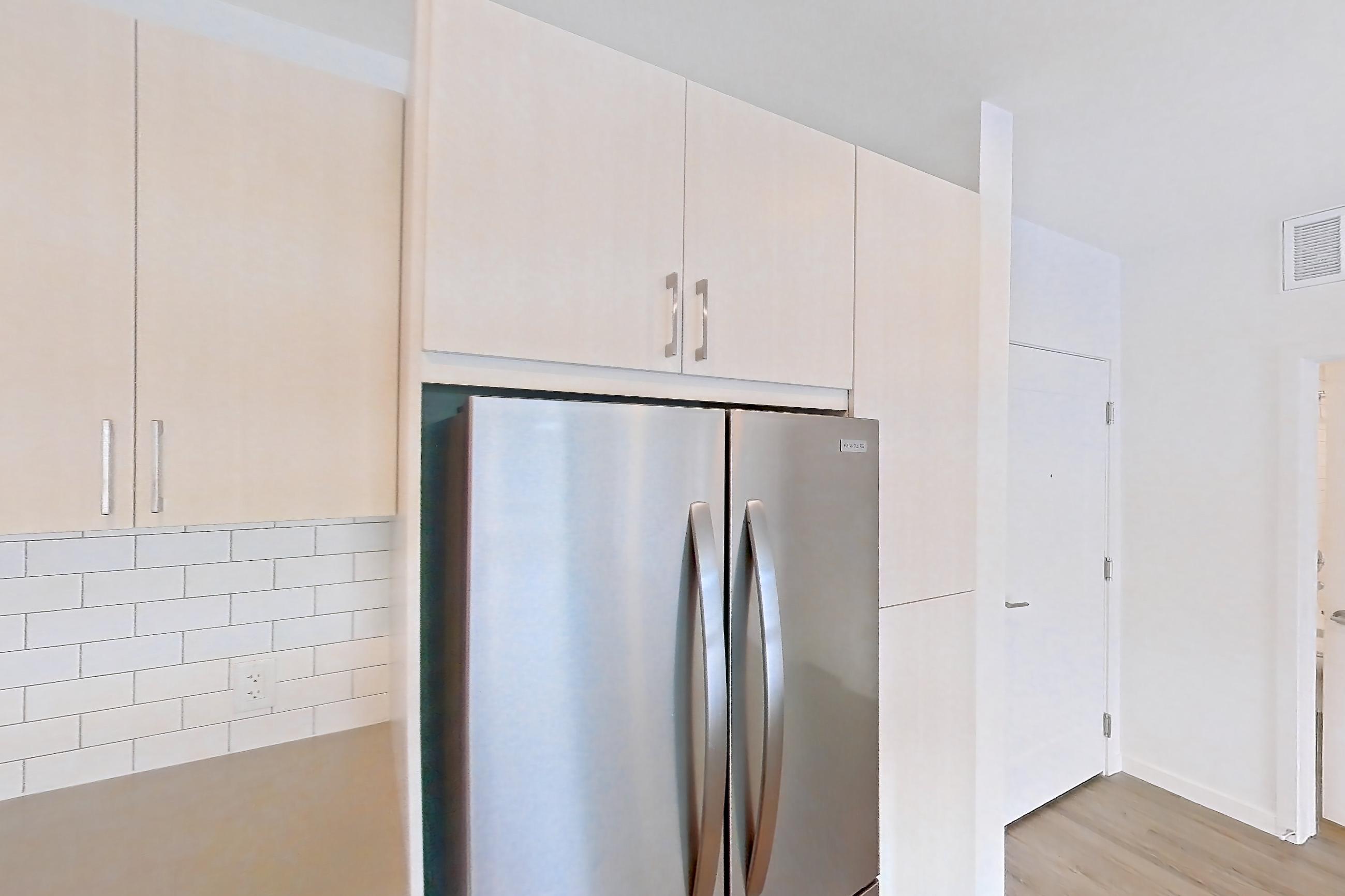Kitchen with dishwasher, electric range, light countertops, light wood-finish flooring, microwave, oven/range, refrigerator, and stainless steel appliances, Apartment 440 at Braxton