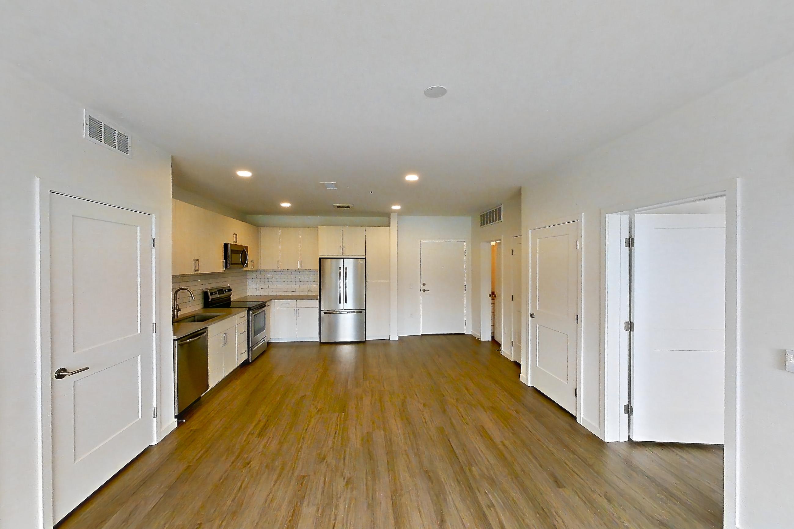 Living space with dark countertops, dark wood-finish flooring, dishwasher, electric range, oven/range, refrigerator, and stainless steel appliances, Apartment 440 at Braxton