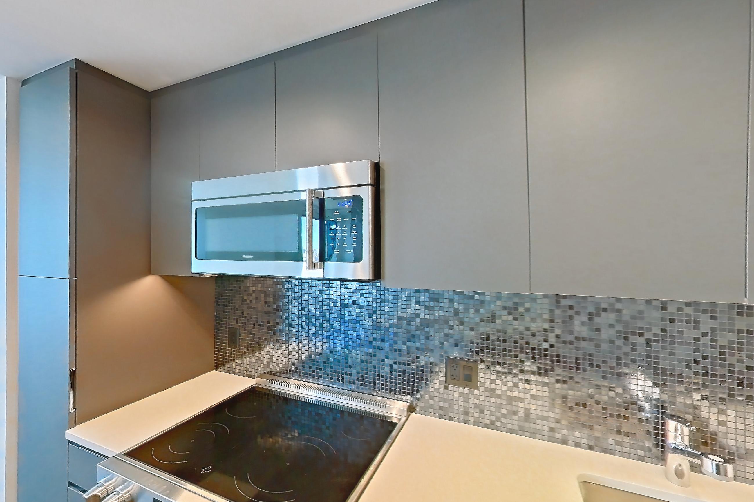 Kitchen with electric range, light countertops, light wood-finish flooring, microwave, oven/range, and stainless steel appliances, Apartment 2701 at The Sudbury