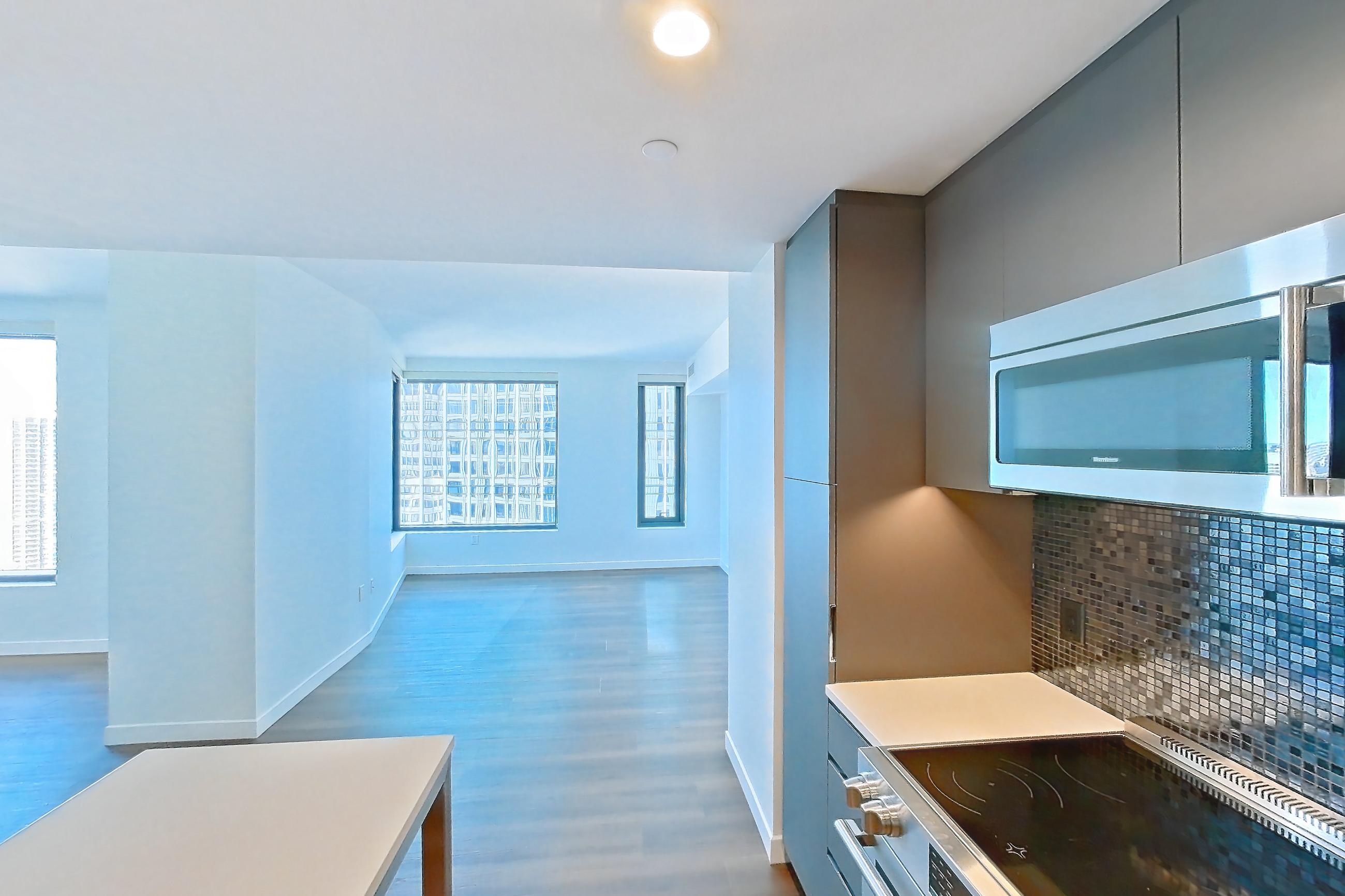 Kitchen with electric range, light countertops, light wood-finish flooring, microwave, oven/range, and stainless steel appliances, Apartment 2701 at The Sudbury