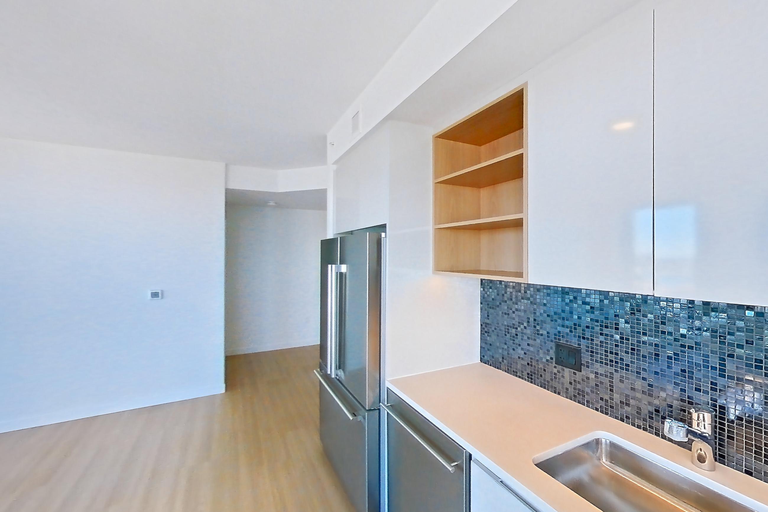 Kitchen with cooktop, electric cooktop, electric range, light countertops, light wood-finish flooring, microwave, oven/range, refrigerator, and stainless steel appliances, Apartment 2402 at The Sudbury