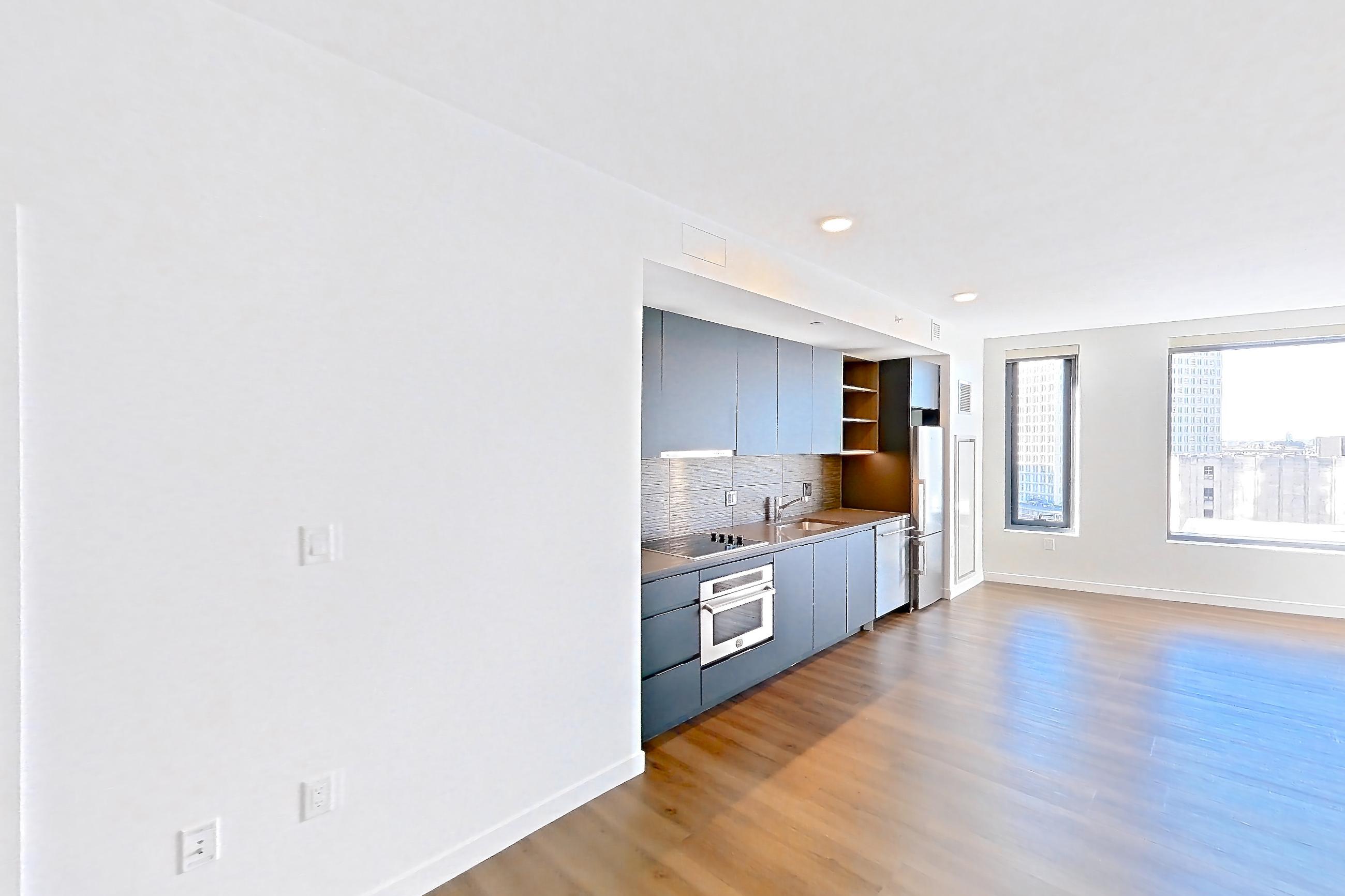 Living space 1 with black appliances, cooktop, dark stainless steel countertops, dark wood-finish flooring, electric cooktop, oven/range, and stainless steel appliances, Apartment 1414 at The Sudbury