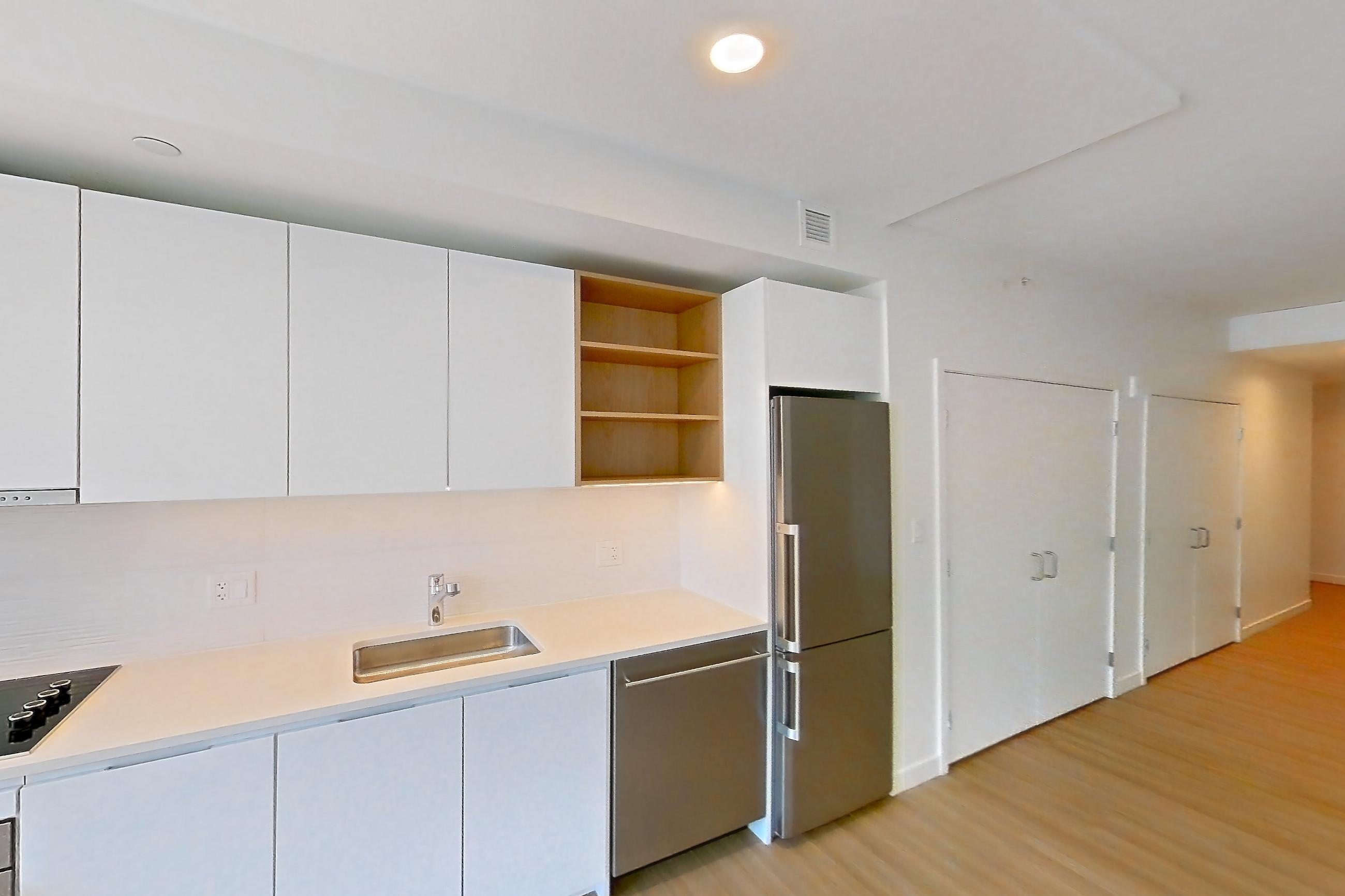 Kitchen with black appliances, cooktop, dishwasher, electric cooktop, light countertops, light wood-finish flooring, oven/range, refrigerator, and stainless steel appliances, Apartment 1112 at The Sudbury