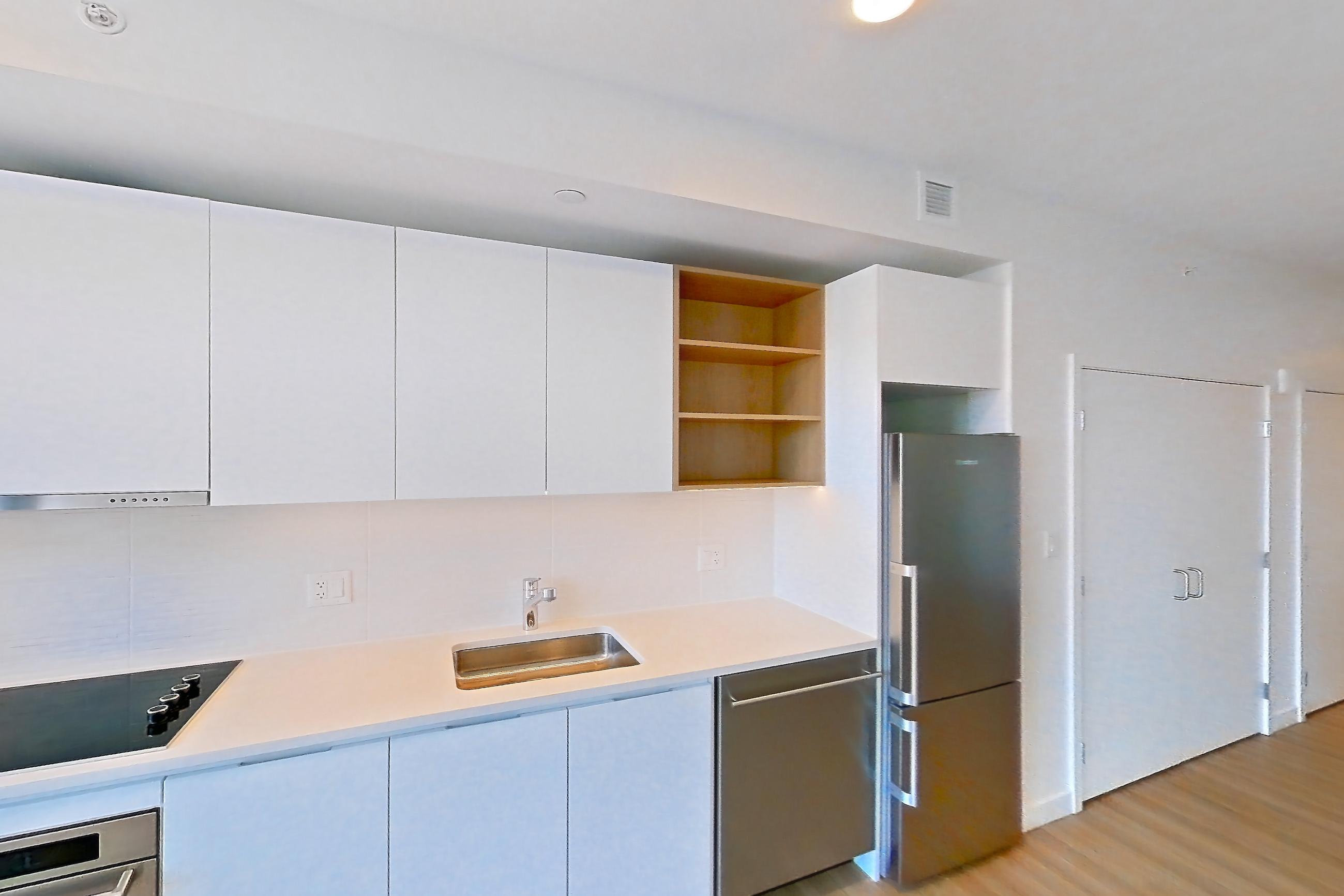 Kitchen with black appliances, cooktop, dishwasher, electric cooktop, light countertops, light wood-finish flooring, oven/range, refrigerator, and stainless steel appliances, Apartment 2812 at The Sudbury