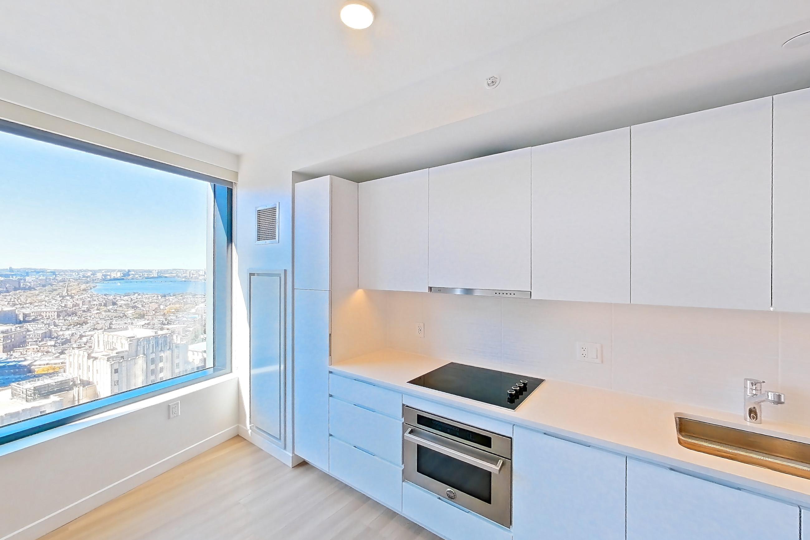 Kitchen with black appliances, cooktop, dishwasher, electric cooktop, light countertops, light wood-finish flooring, oven/range, refrigerator, and stainless steel appliances, Apartment 2812 at The Sudbury
