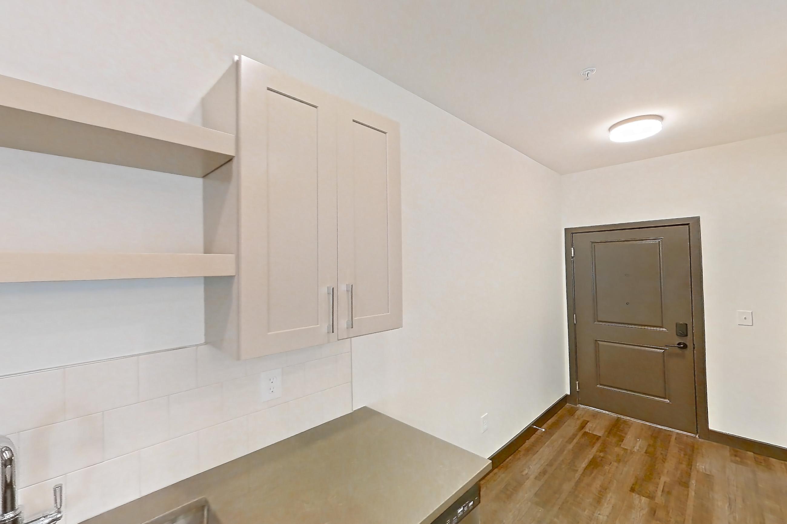 Kitchen with dark countertops, dark wood-finish flooring, dishwasher, gas range, oven/range, and stainless steel appliances, Apartment 3102 at The Grounds