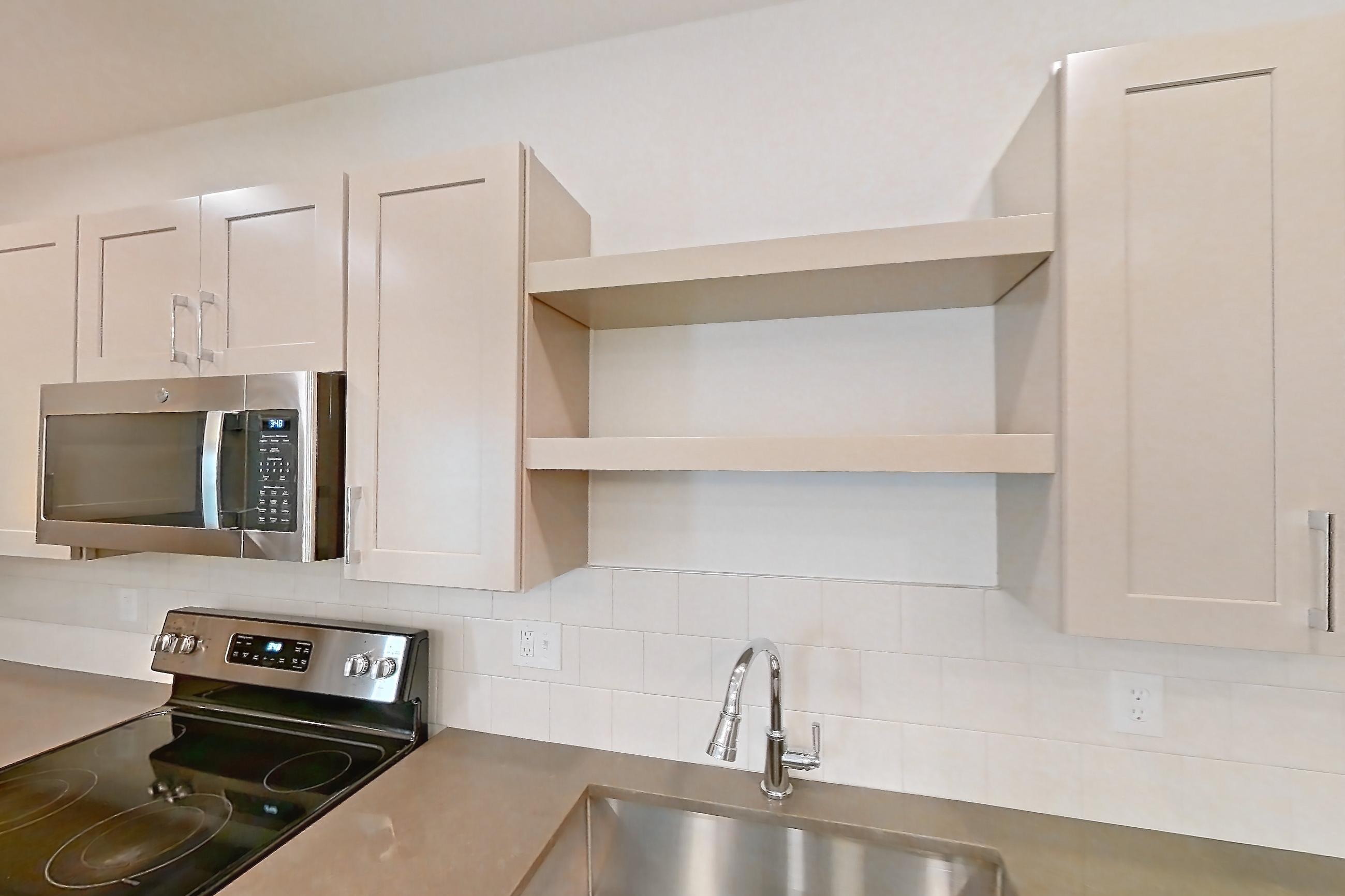 Kitchen with dark countertops, dark wood-finish flooring, dishwasher, gas range, oven/range, and stainless steel appliances, Apartment 3102 at The Grounds