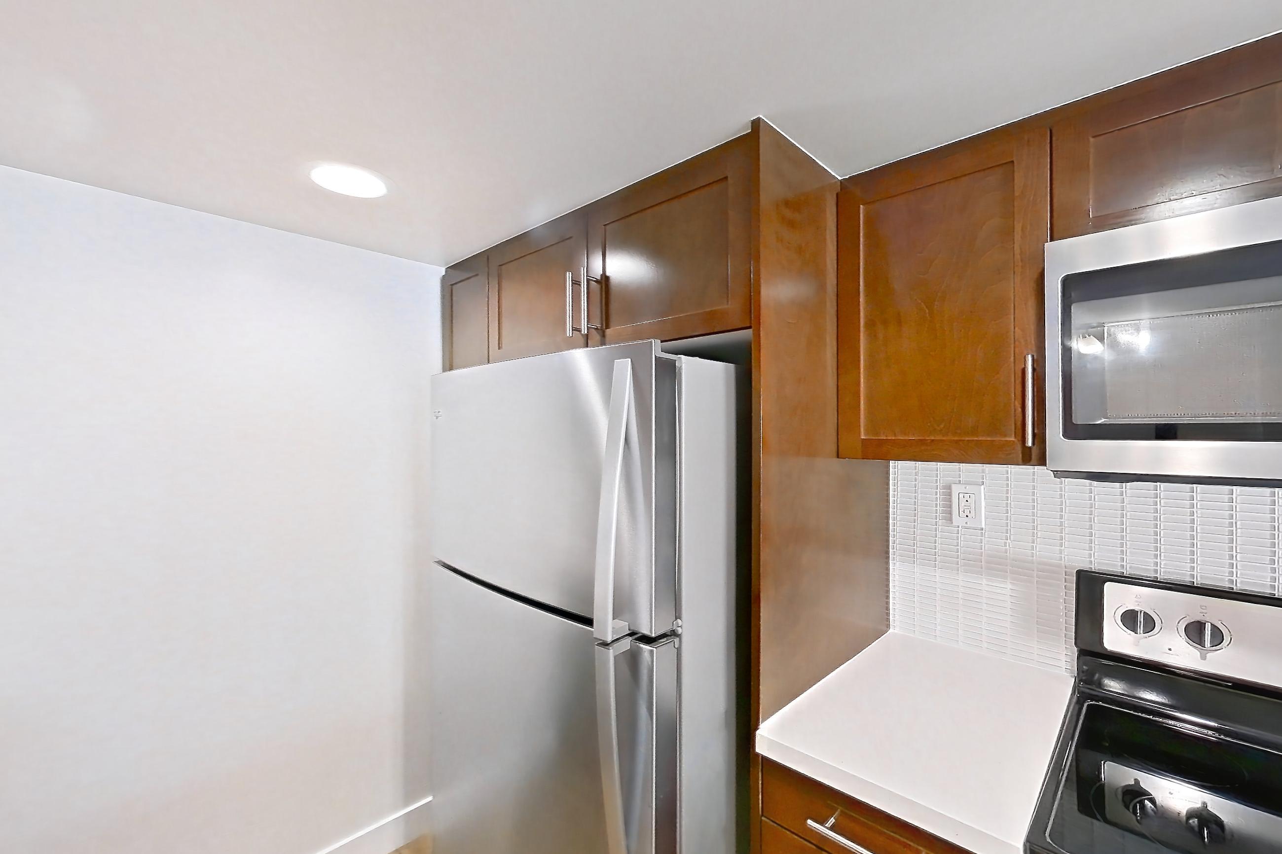 Kitchen with dishwasher, light countertops, light wood-finish flooring, refrigerator, and stainless steel appliances, Apartment 1215 at Wayfarer Apartments + Marina