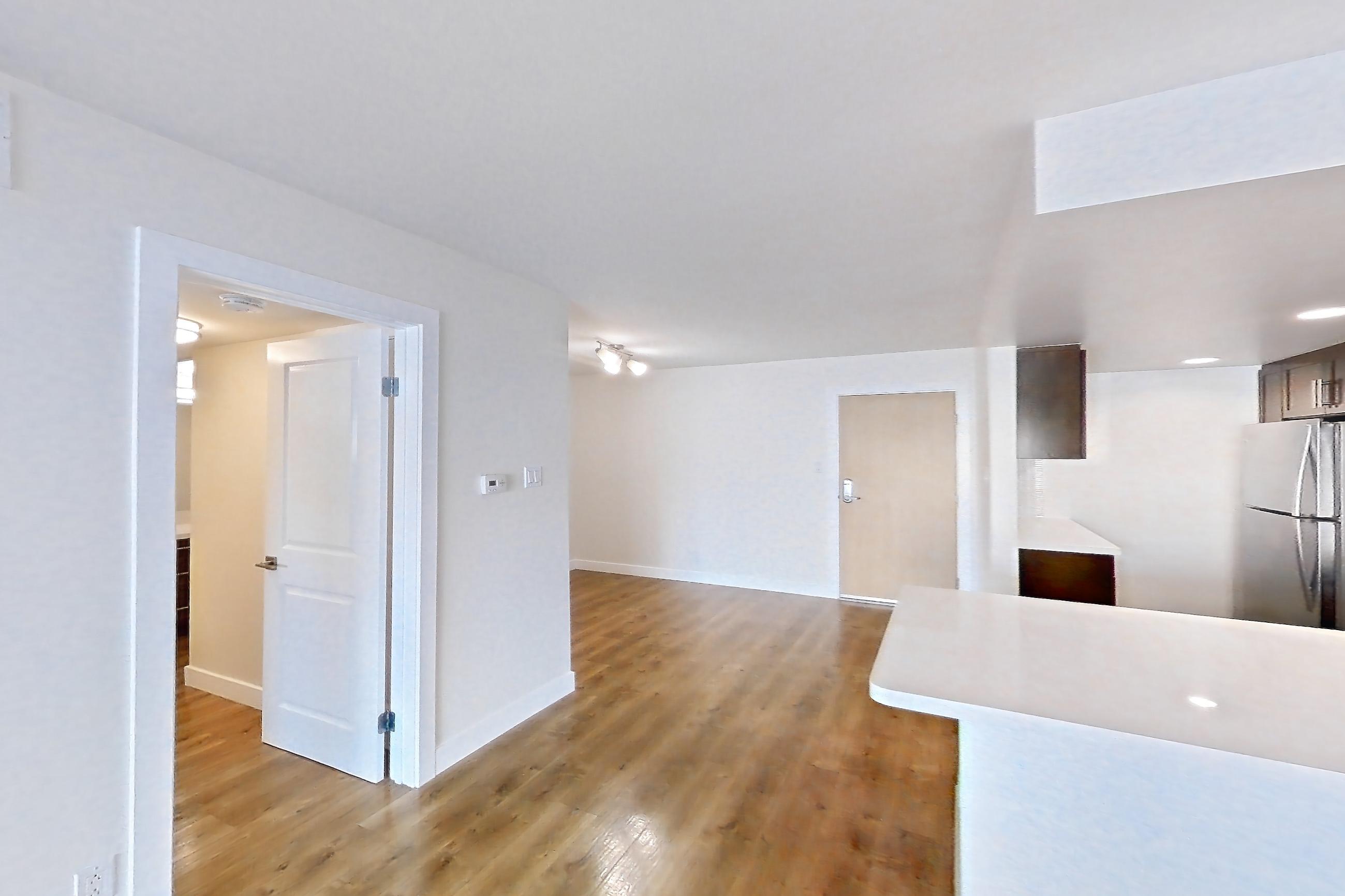 Living room with electric range, light countertops, light wood-finish flooring, microwave, oven/range, refrigerator, stainless steel appliances, and white appliances, Apartment 1215 at Wayfarer Apartments + Marina