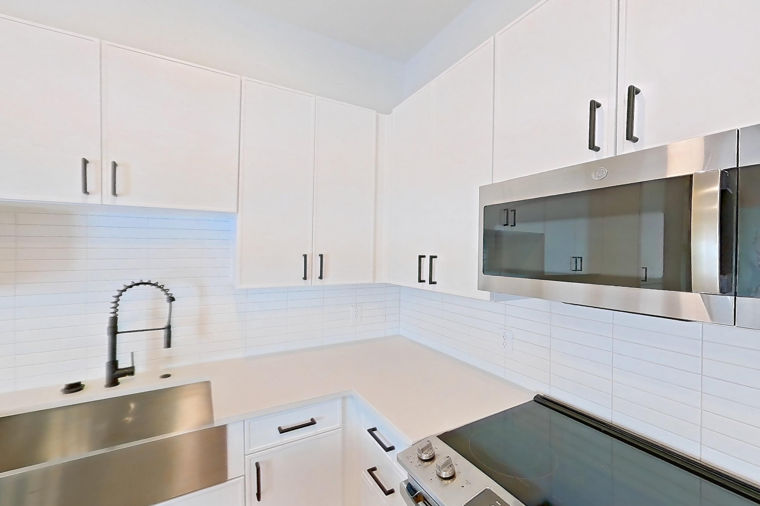 Kitchen with dark wood-finish flooring, dishwasher, electric range, light countertops, light stone countertops, light wood-finish flooring, oven/range, refrigerator, and stainless steel appliances, Apartment 517 at Lantower West Love