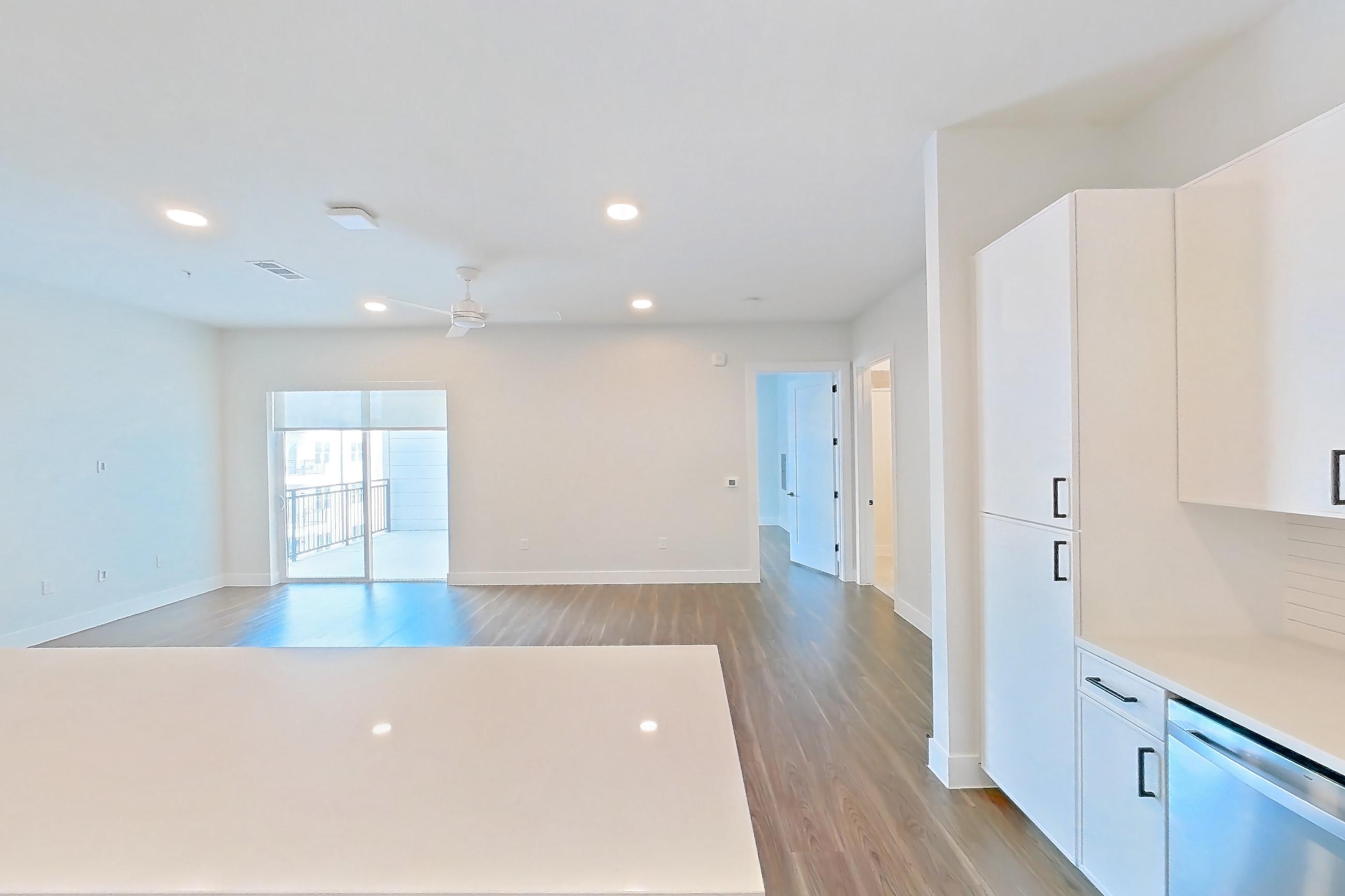 Kitchen with dark wood-finish flooring, dishwasher, electric range, light countertops, light stone countertops, light wood-finish flooring, oven/range, refrigerator, and stainless steel appliances, Apartment 517 at Lantower West Love