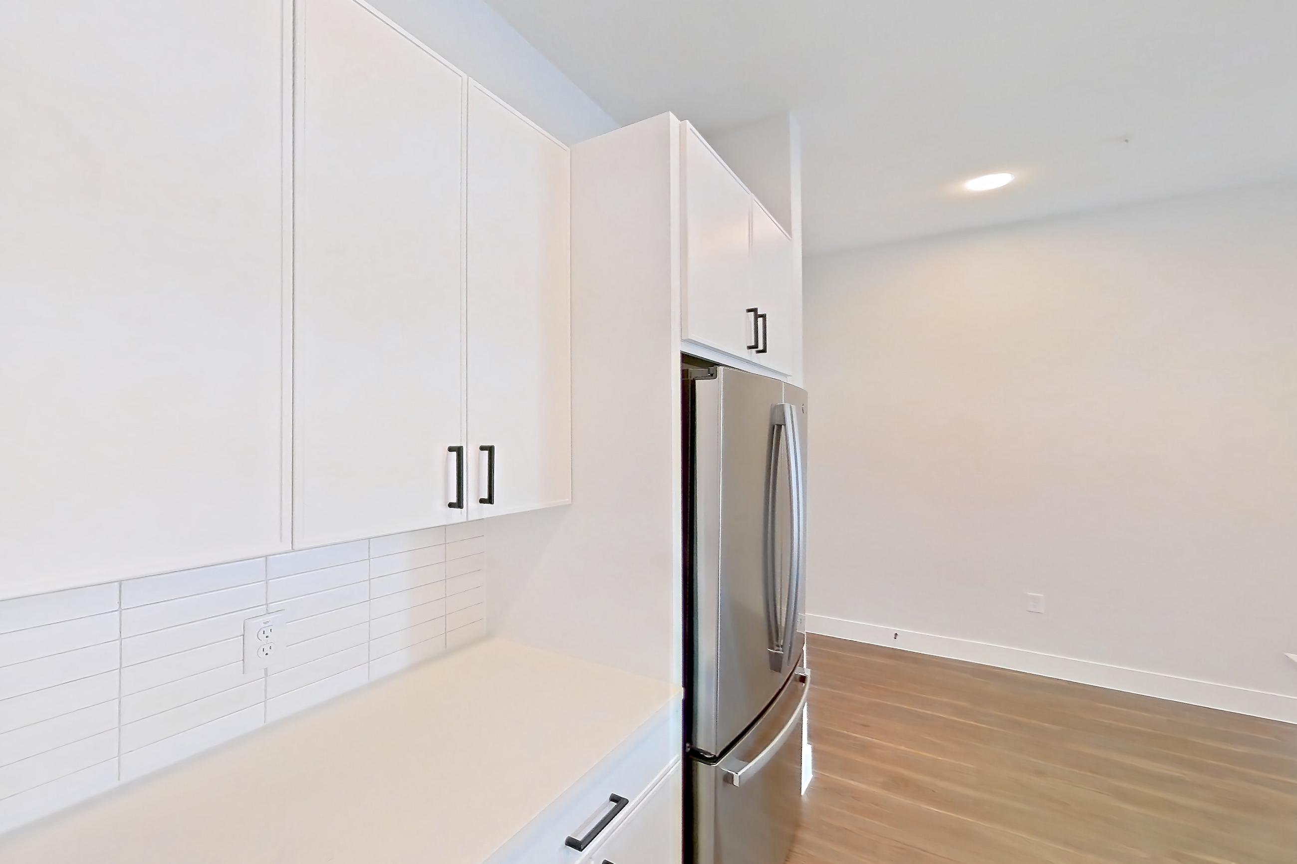 Kitchen with dark wood-finish flooring, dishwasher, electric range, light countertops, light stone countertops, light wood-finish flooring, oven/range, refrigerator, and stainless steel appliances, Apartment 517 at Lantower West Love