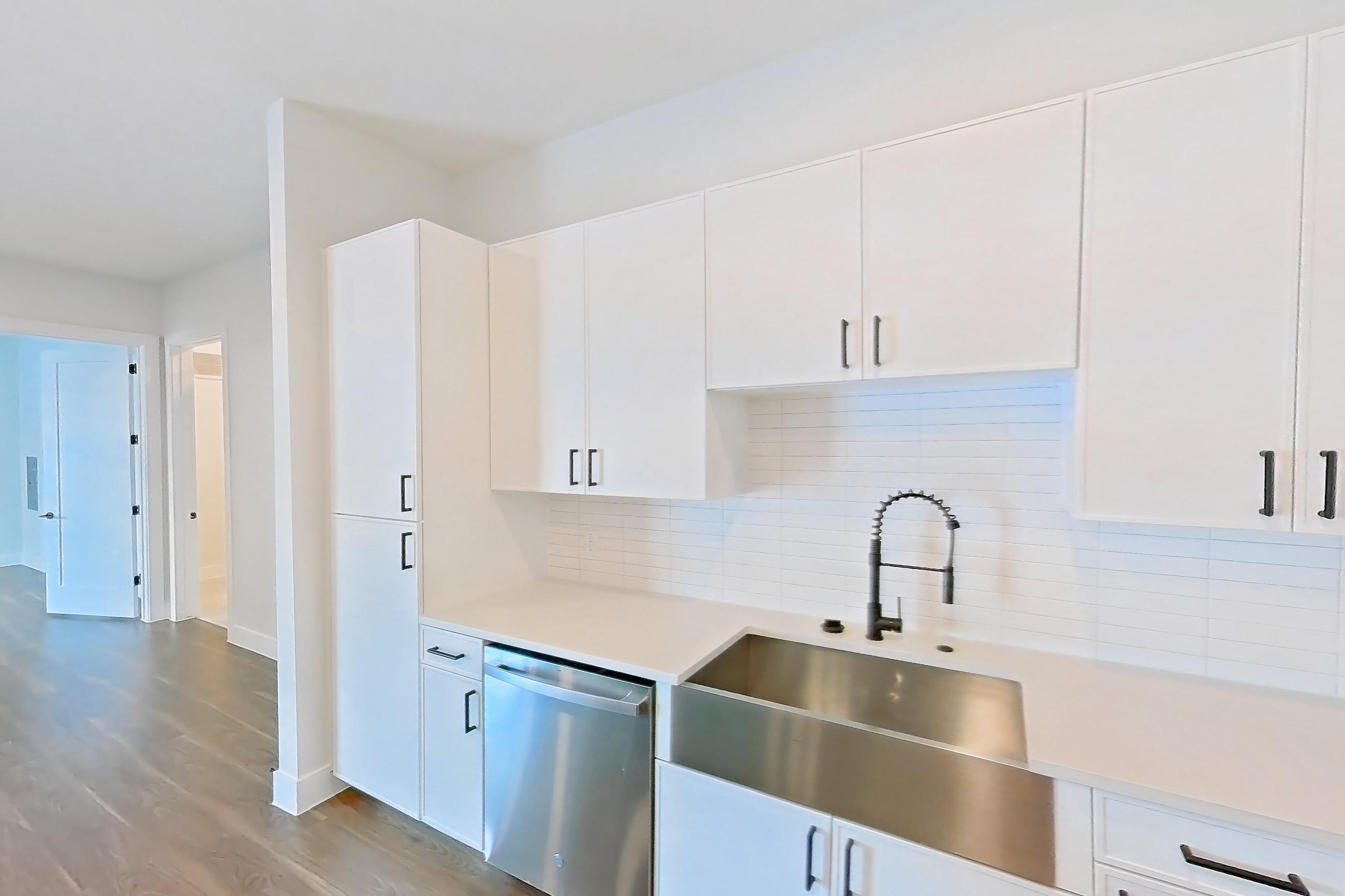 Kitchen with dark wood-finish flooring, dishwasher, electric range, light countertops, light stone countertops, light wood-finish flooring, oven/range, refrigerator, and stainless steel appliances, Apartment 517 at Lantower West Love