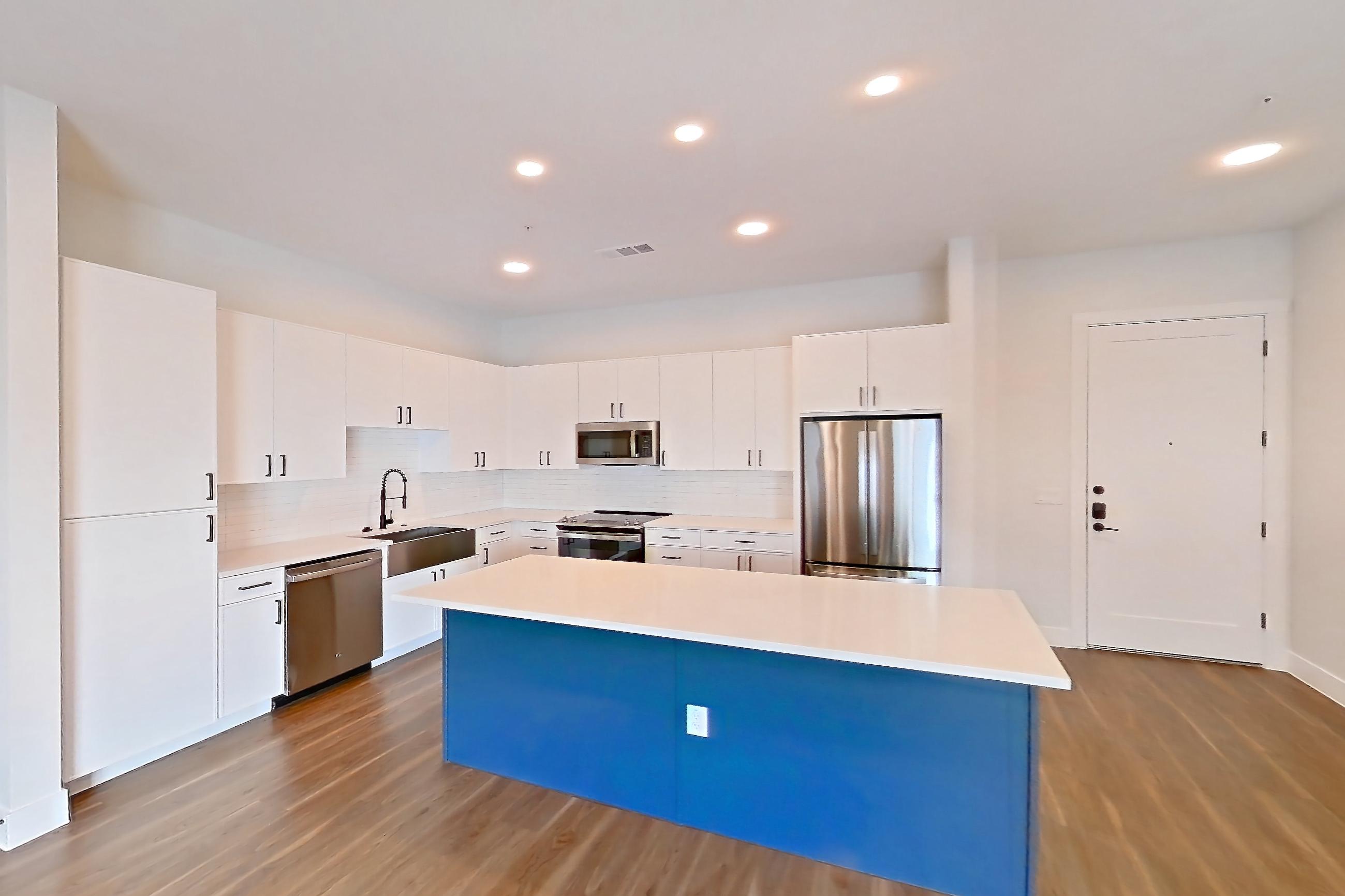 Living room with dark wood-finish flooring, dishwasher, electric range, light countertops, light wood-finish flooring, oven/range, refrigerator, and stainless steel appliances, Apartment 517 at Lantower West Love