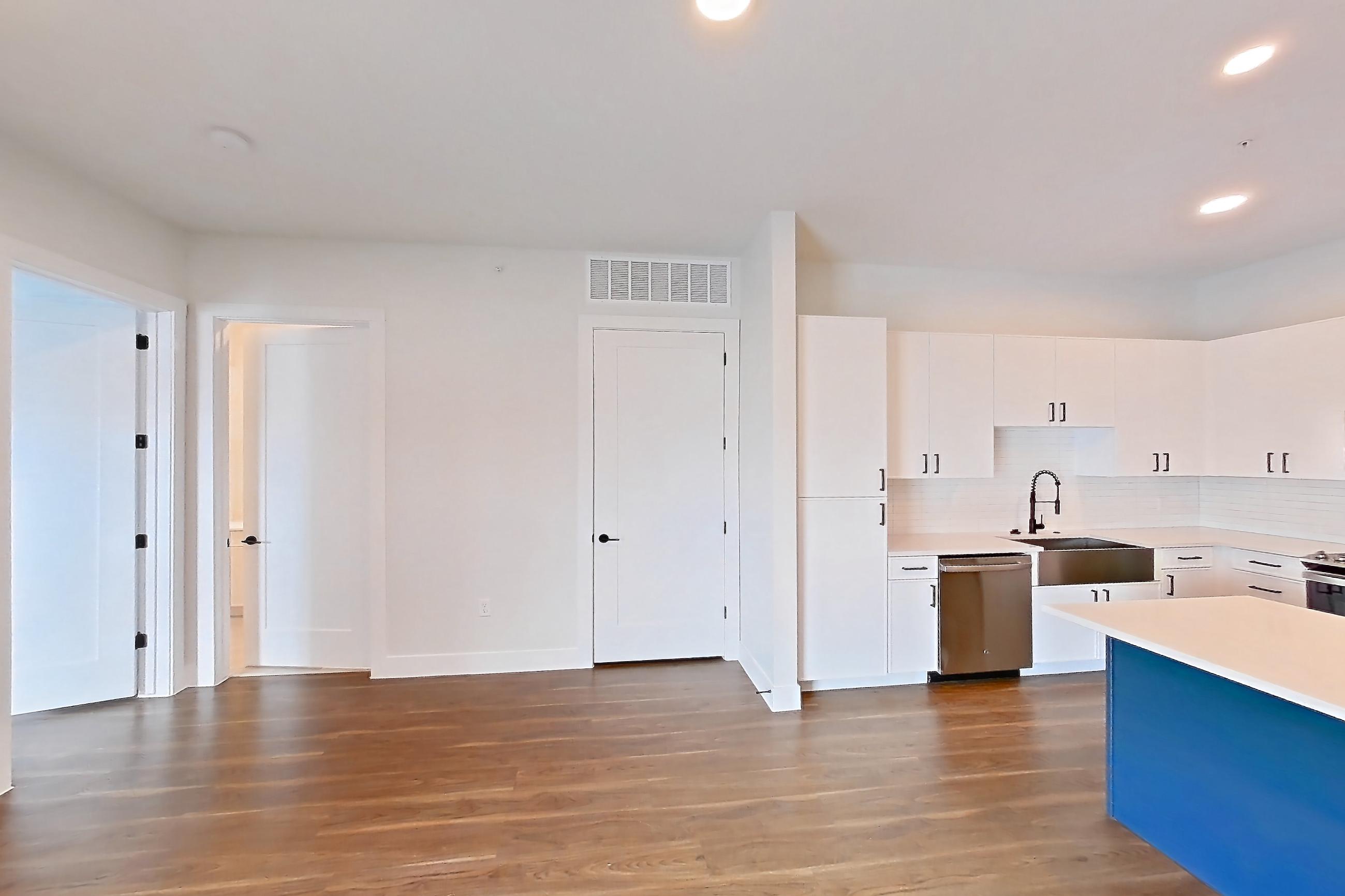 Living room with dark wood-finish flooring, dishwasher, electric range, light countertops, light wood-finish flooring, oven/range, refrigerator, and stainless steel appliances, Apartment 517 at Lantower West Love