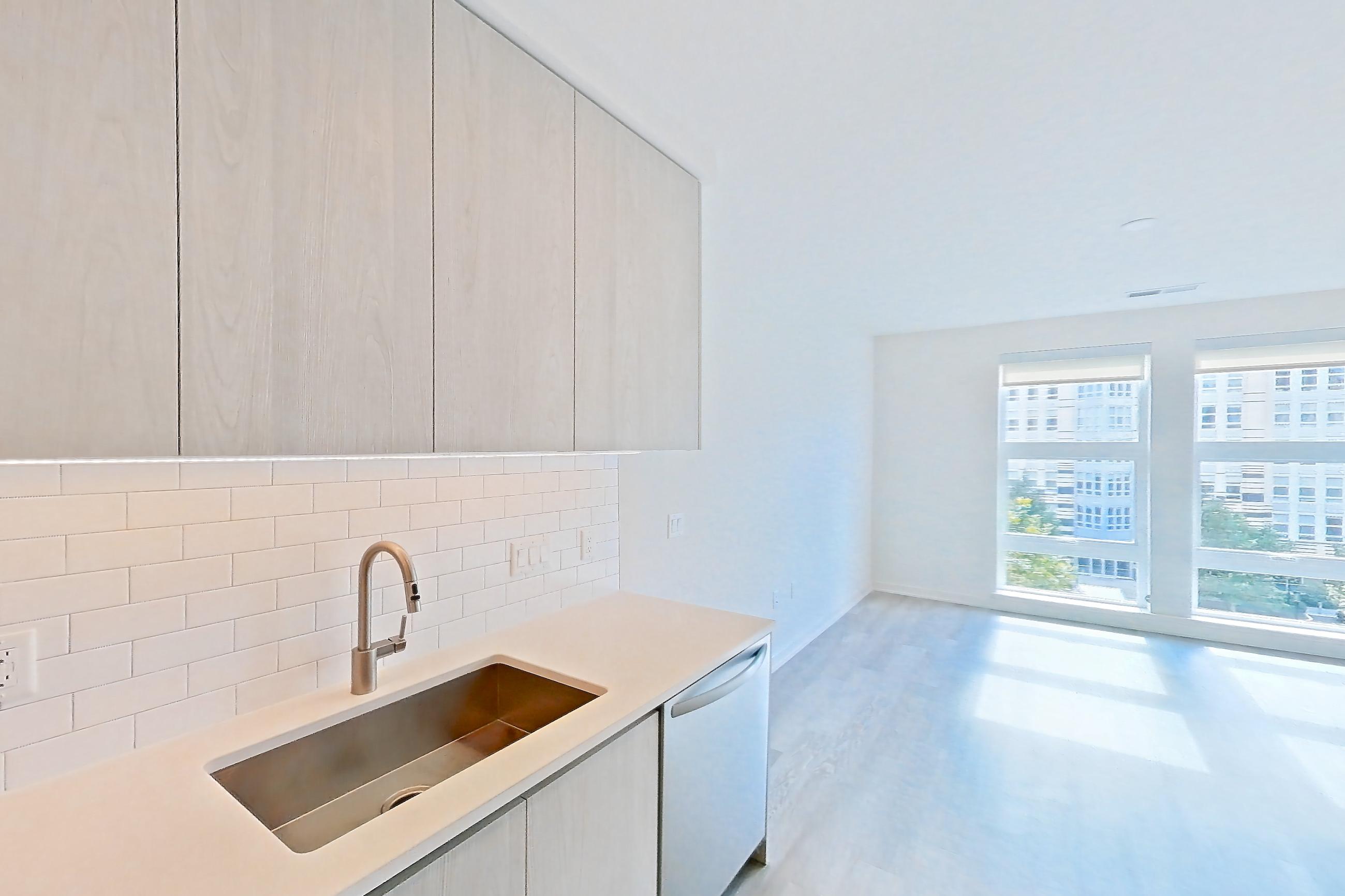 Kitchen with dishwasher, electric range, light countertops, light stone countertops, light wood-finish flooring, microwave, oven/range, refrigerator, and stainless steel appliances, Apartment 3421 at Platform (VA)