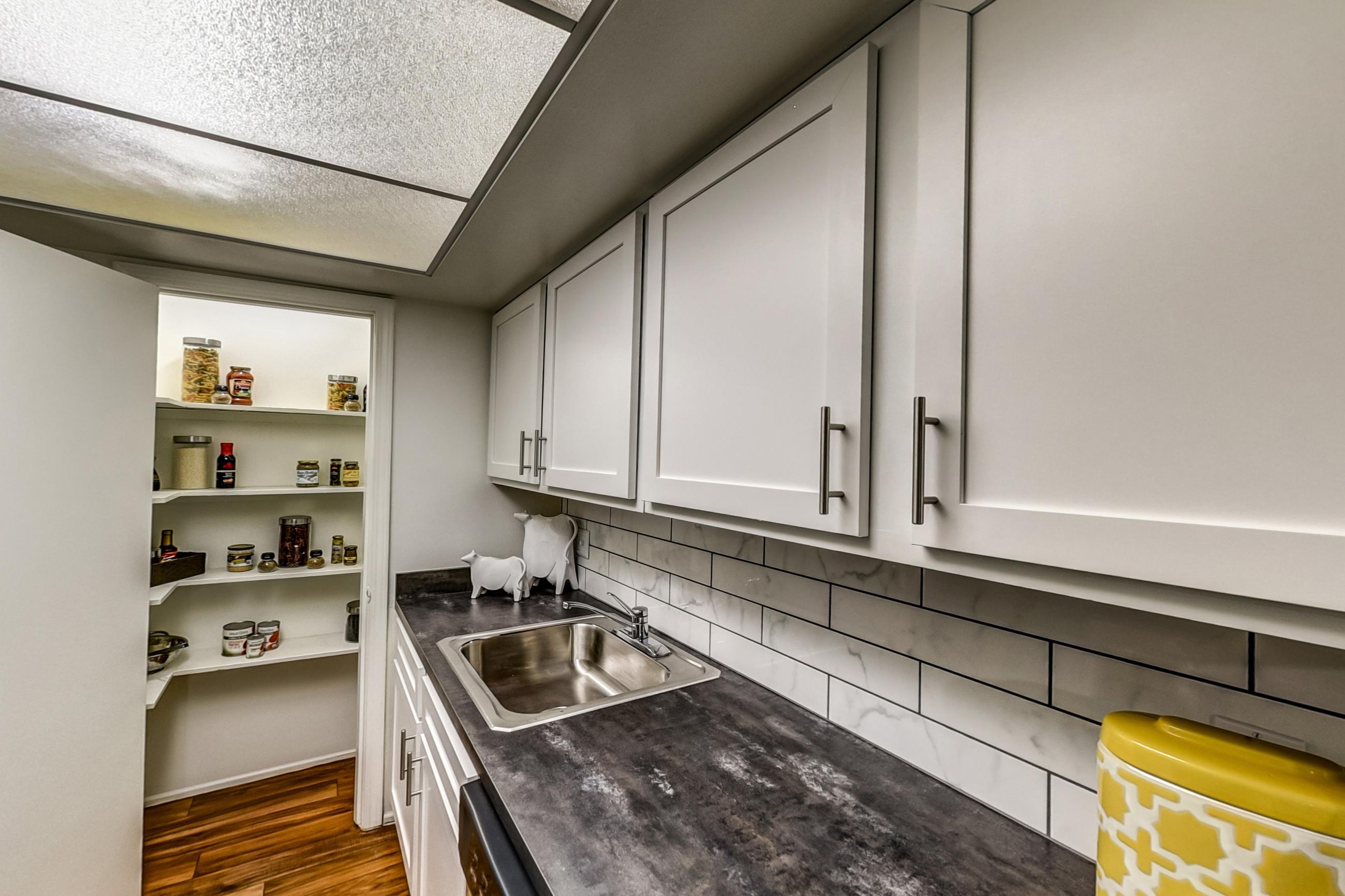Kitchen with dark countertops, electric range, light wood-finish flooring, oven/range, refrigerator, and stainless steel appliances, Apartment Model 1 at Canterbury Green