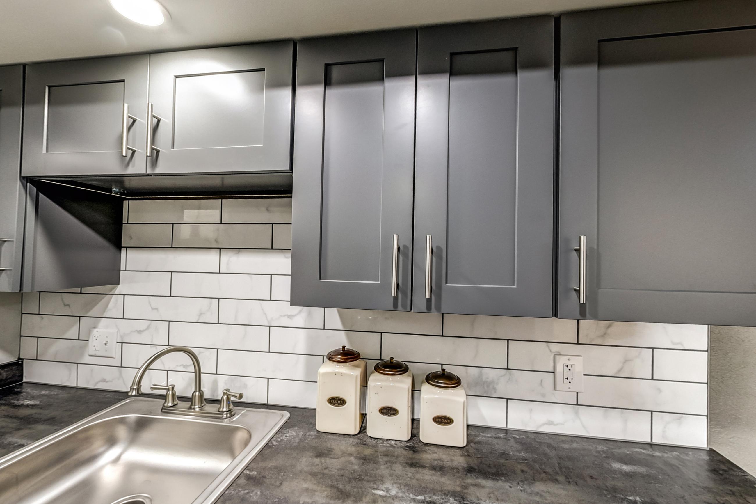 Kitchen with black appliances, dark countertops, dishwasher, electric range, light wood-finish flooring, oven/range, range hood, and refrigerator, Apartment Model 3 at Canterbury Green