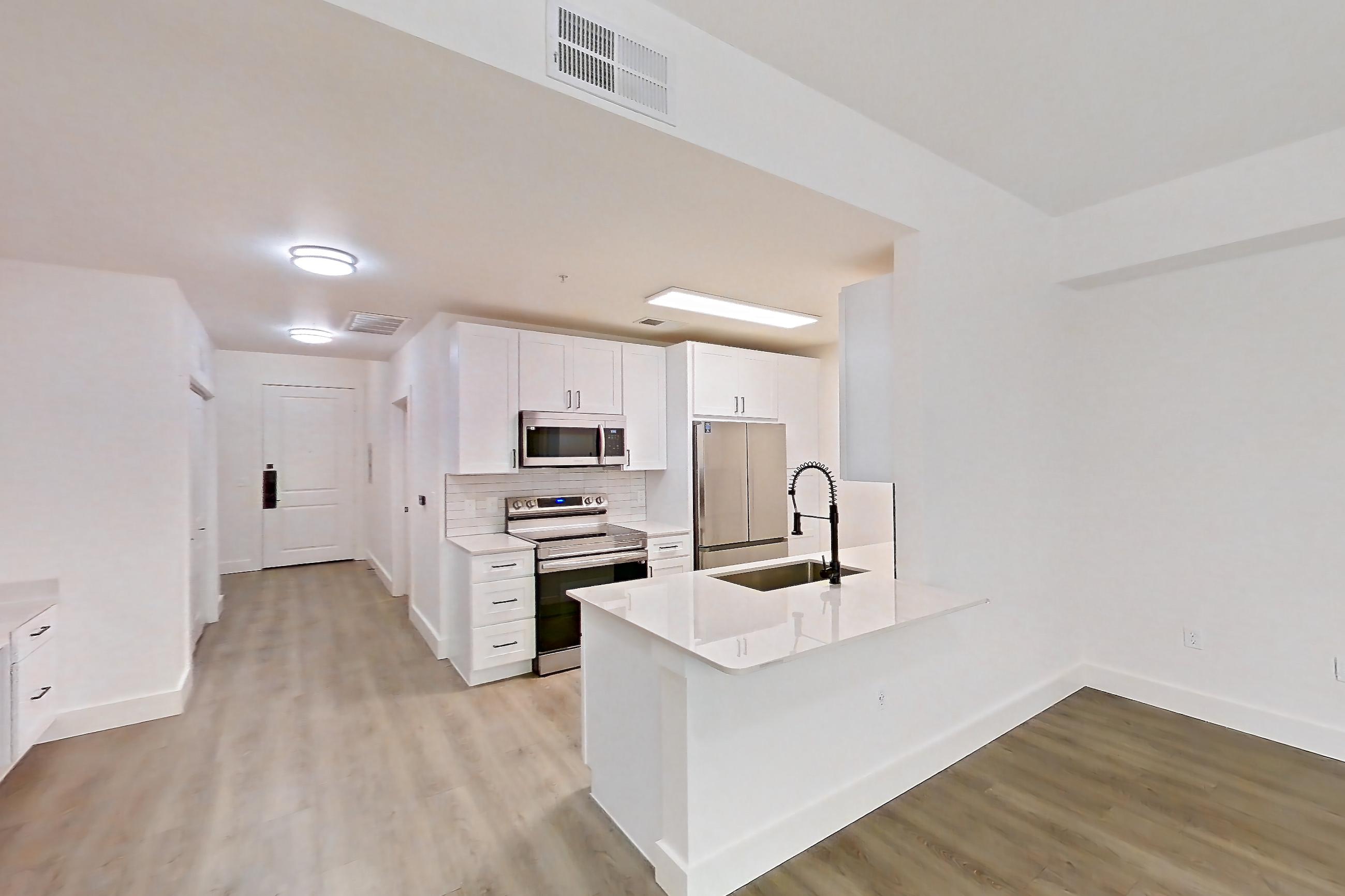 Living space with electric range, light stone countertops, light wood-finish flooring, oven/range, refrigerator, and stainless steel appliances, Apartment 319 at Cortland at West Village