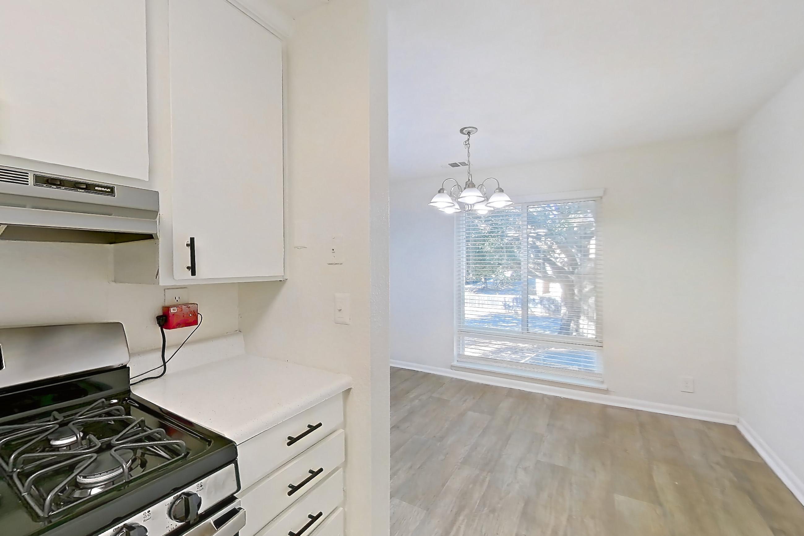 Kitchen with dishwasher, gas range, light countertops, light wood-finish flooring, oven/range, range hood, refrigerator, and stainless steel appliances, Apartment H1536D at The Legacy at Druid Hills
