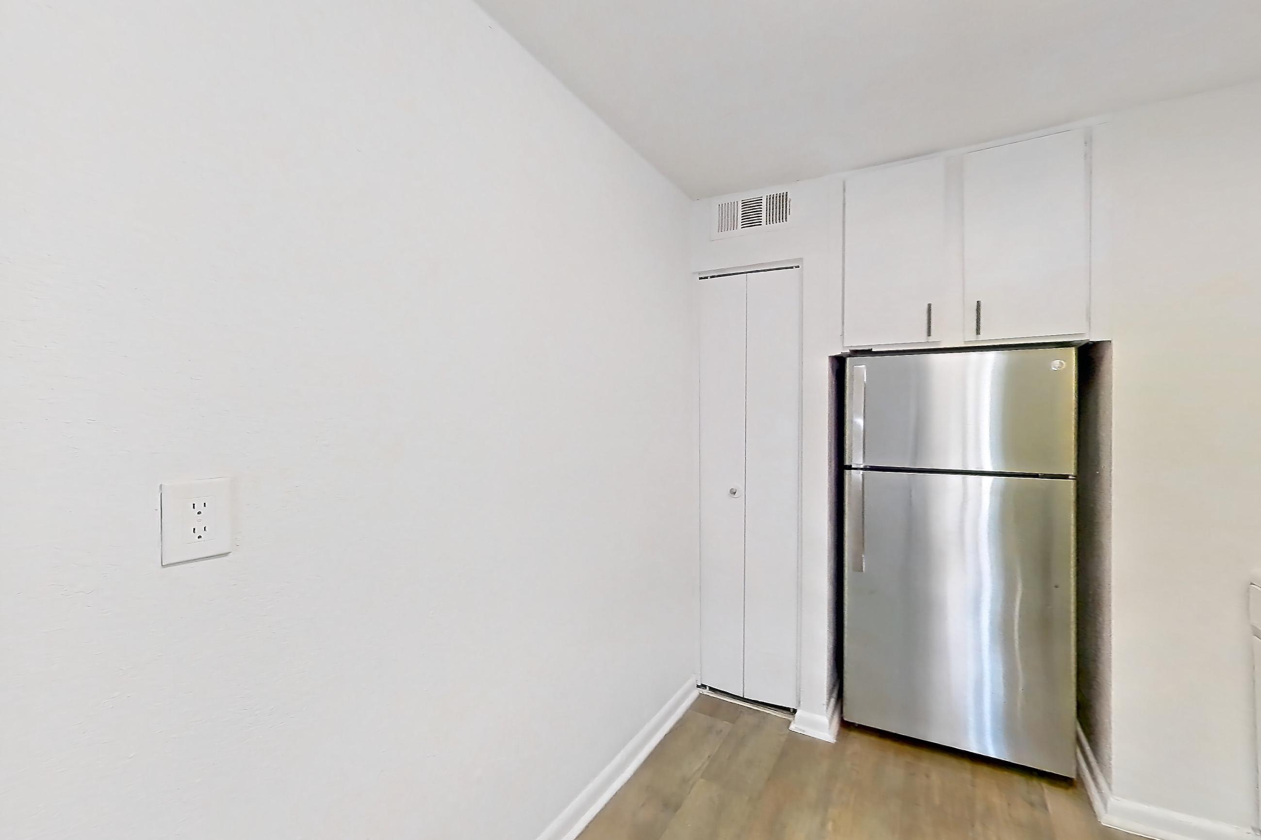 Kitchen with dishwasher, gas range, light countertops, light wood-finish flooring, oven/range, range hood, refrigerator, and stainless steel appliances, Apartment H1536D at The Legacy at Druid Hills