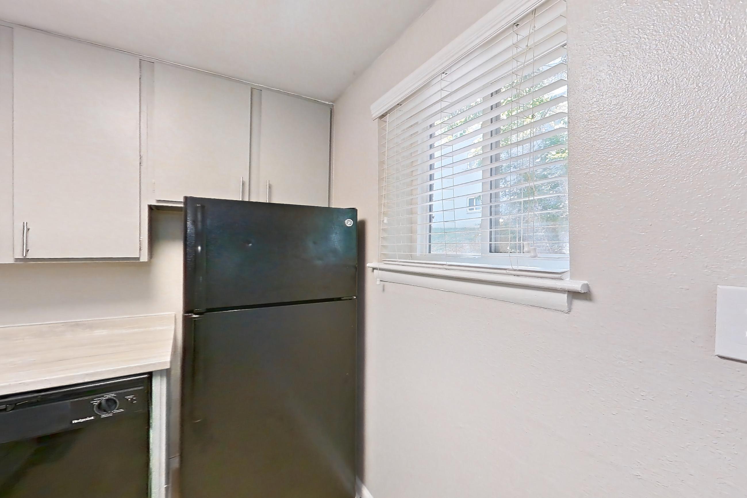 Kitchen with black appliances, dishwasher, gas range, light countertops, light wood-finish flooring, oven/range, range hood, and refrigerator, Apartment L1470A at The Legacy at Druid Hills