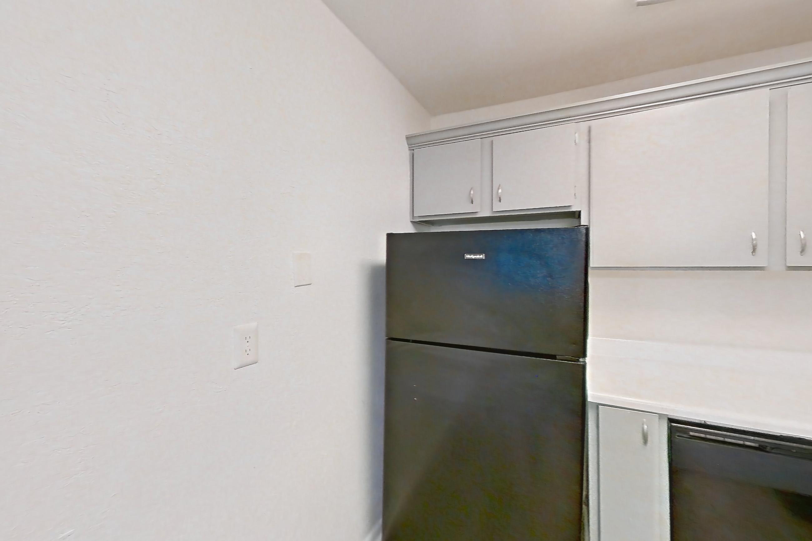 Kitchen with black appliances, dishwasher, gas range, light countertops, light wood-finish flooring, oven/range, and refrigerator, Apartment L1471F at The Legacy at Druid Hills
