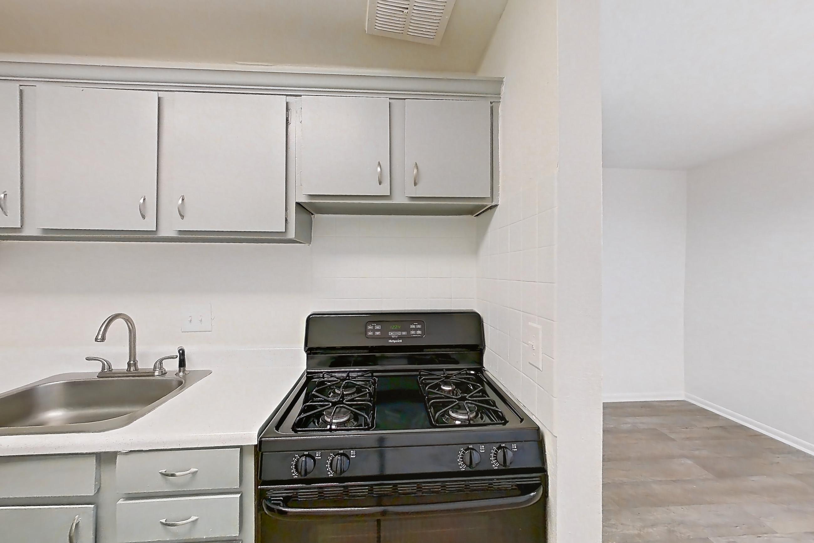 Kitchen with black appliances, dishwasher, gas range, light countertops, light wood-finish flooring, oven/range, and refrigerator, Apartment L1471F at The Legacy at Druid Hills