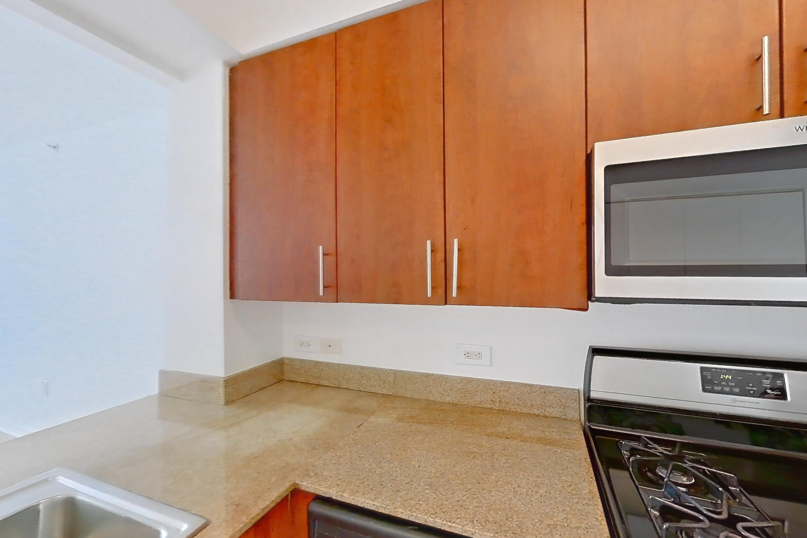 Kitchen with dishwasher, gas range, light countertops, light stone countertops, light tile flooring, light wood-finish flooring, microwave, oven/range, refrigerator, and stainless steel appliances, Apartment 1223 at The Octagon