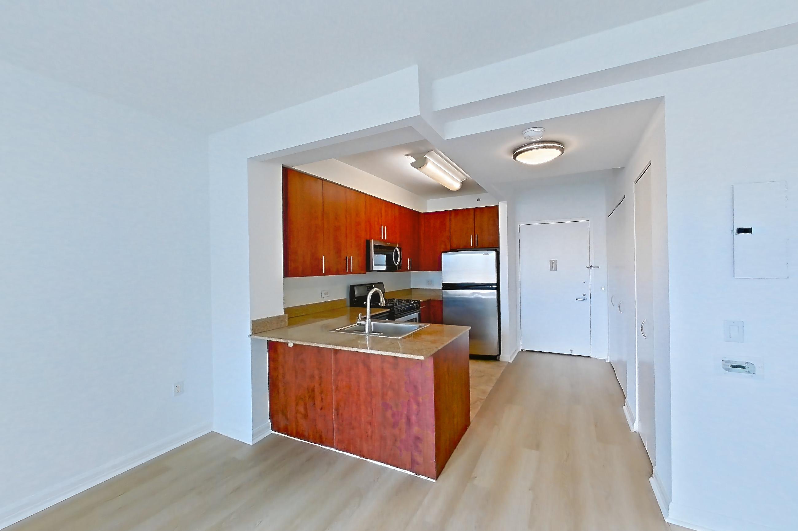 Living space with gas range, light countertops, light wood-finish flooring, oven/range, refrigerator, and stainless steel appliances, Apartment 1223 at The Octagon