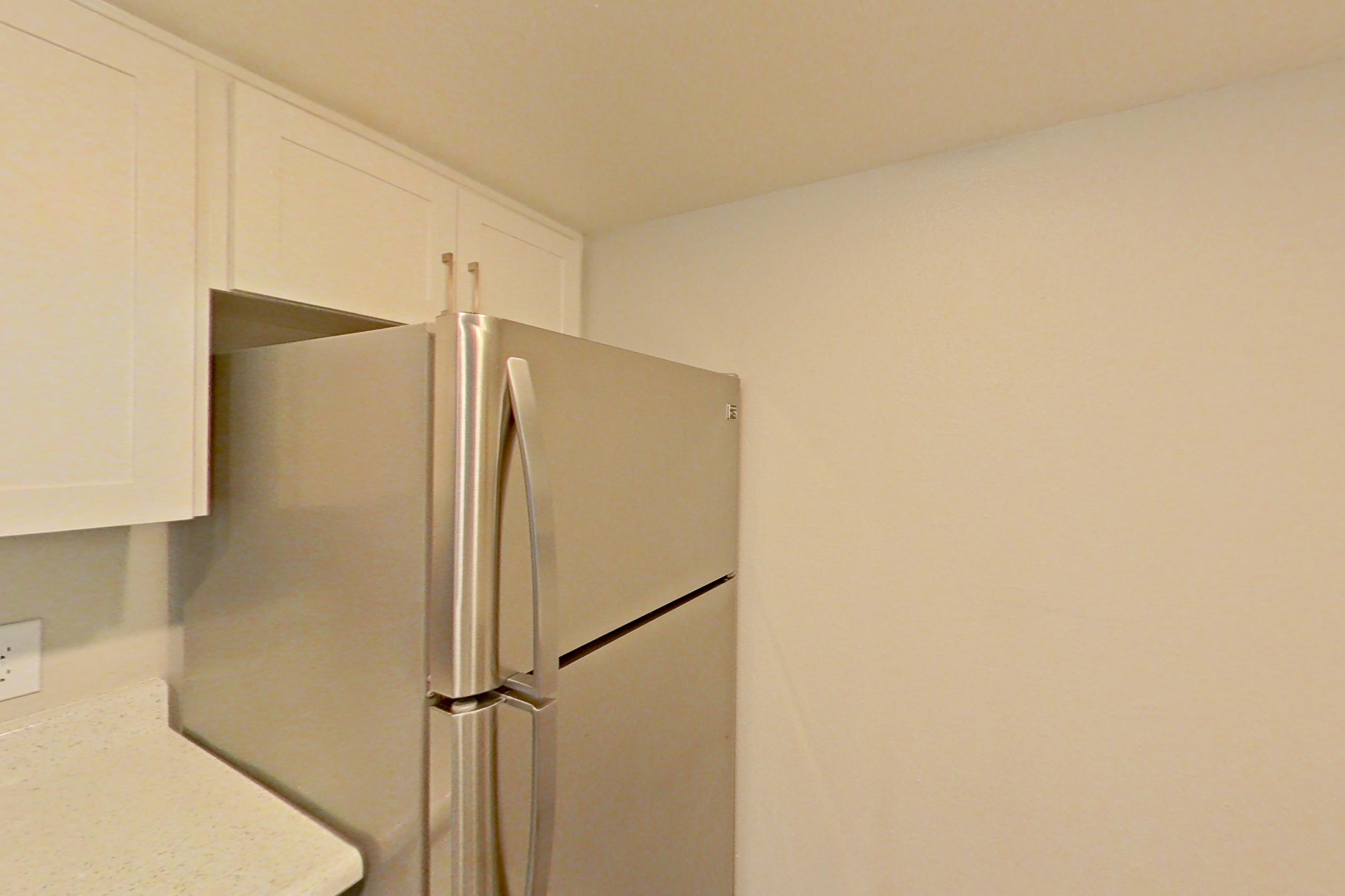 Kitchen with dishwasher, electric range, light countertops, light stone countertops, light wood-finish flooring, microwave, oven/range, refrigerator, and stainless steel appliances, Apartment 20 at Avana Rancho Cucamonga