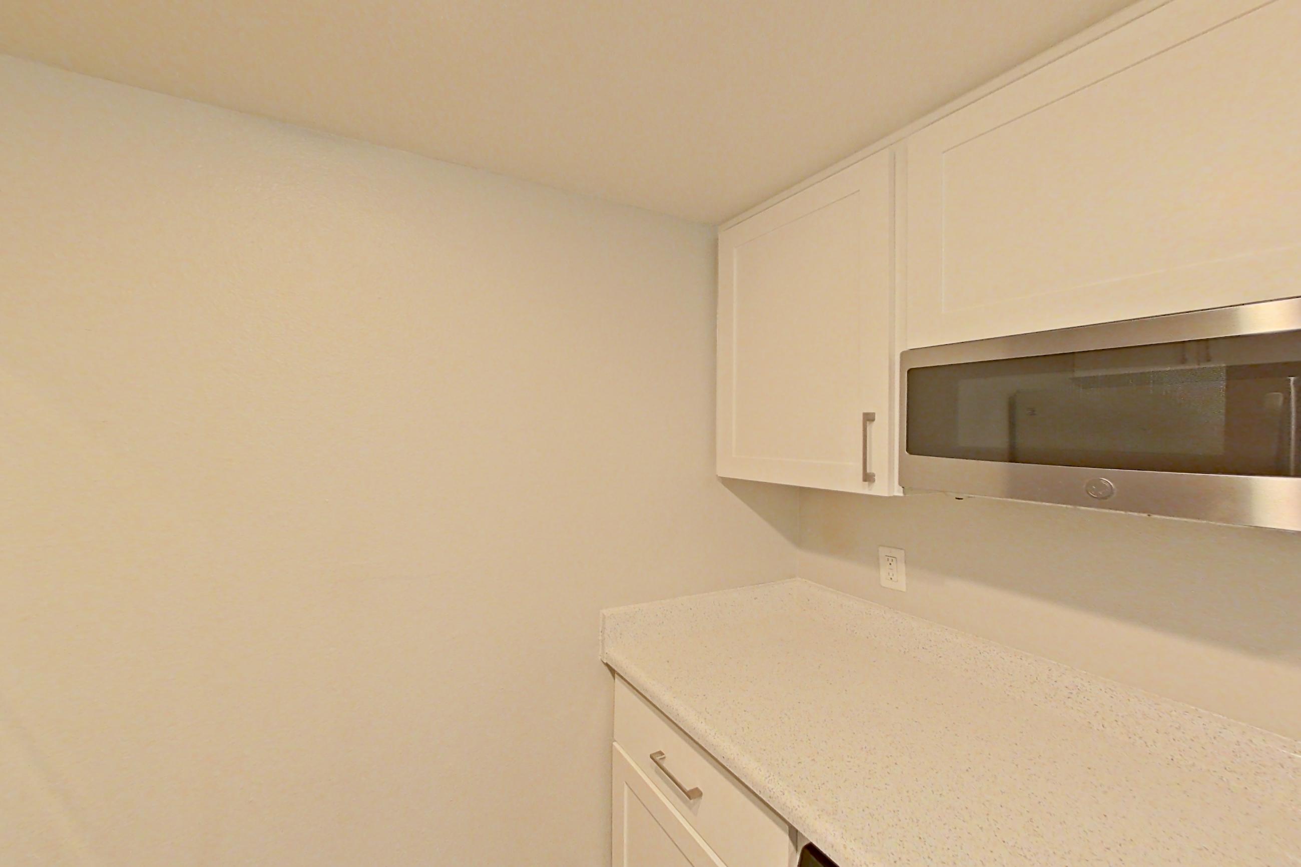 Kitchen with dishwasher, electric range, light countertops, light stone countertops, light wood-finish flooring, microwave, oven/range, refrigerator, and stainless steel appliances, Apartment 20 at Avana Rancho Cucamonga